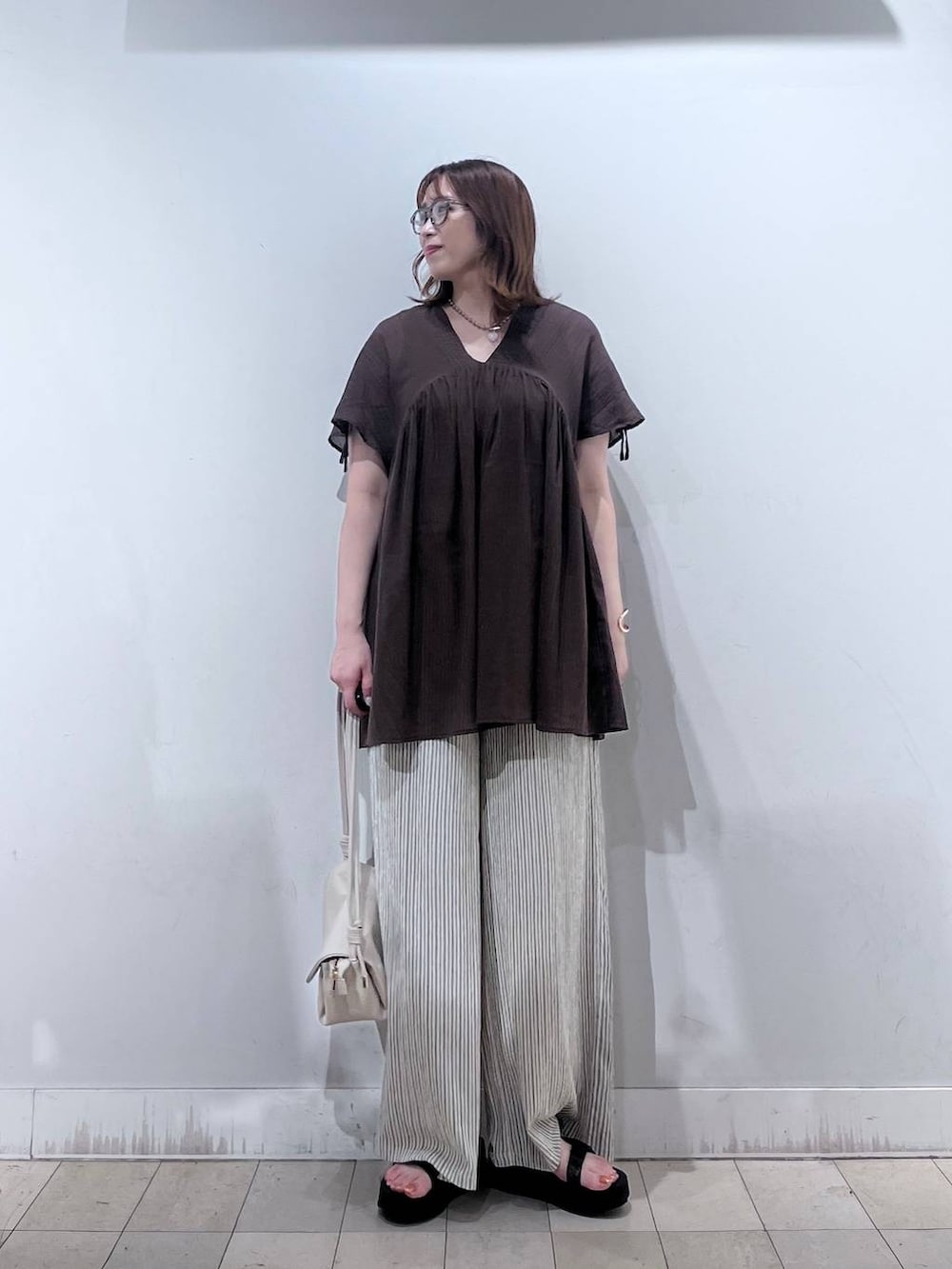 ベージュ系のショルダーバッグ、ベージュ系のその他パンツ、ブラウン系のシャツ/ブラウスを着用したレディースの夏コーディネートの3枚目の写真