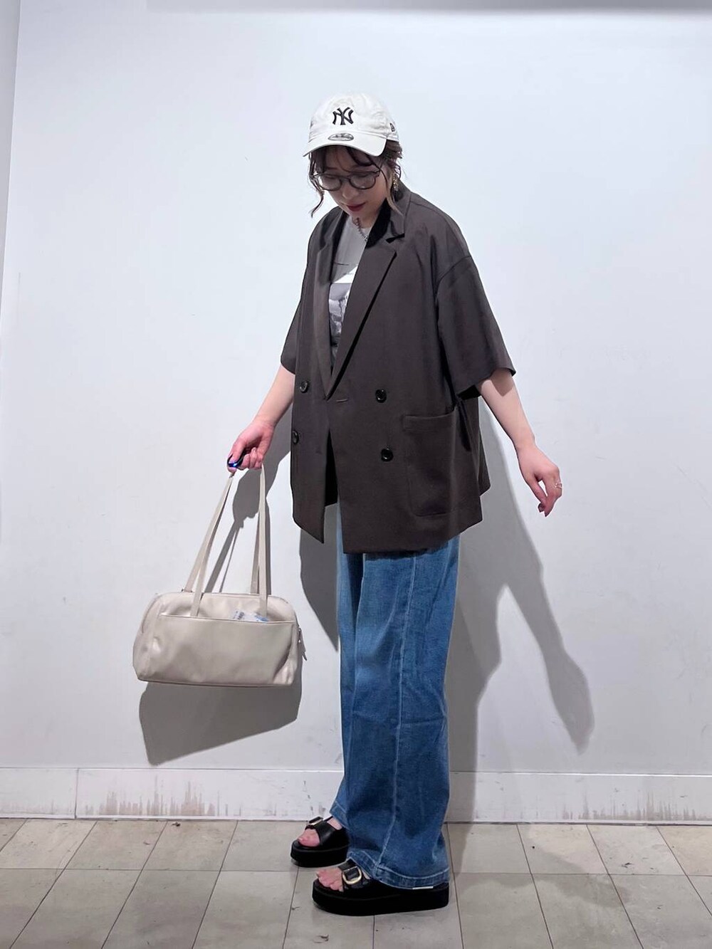 ブルー系のデニムパンツ、ホワイト系のTシャツ/カットソー、ベージュ系のショルダーバッグを着用したレディースの春コーディネートの7枚目の写真