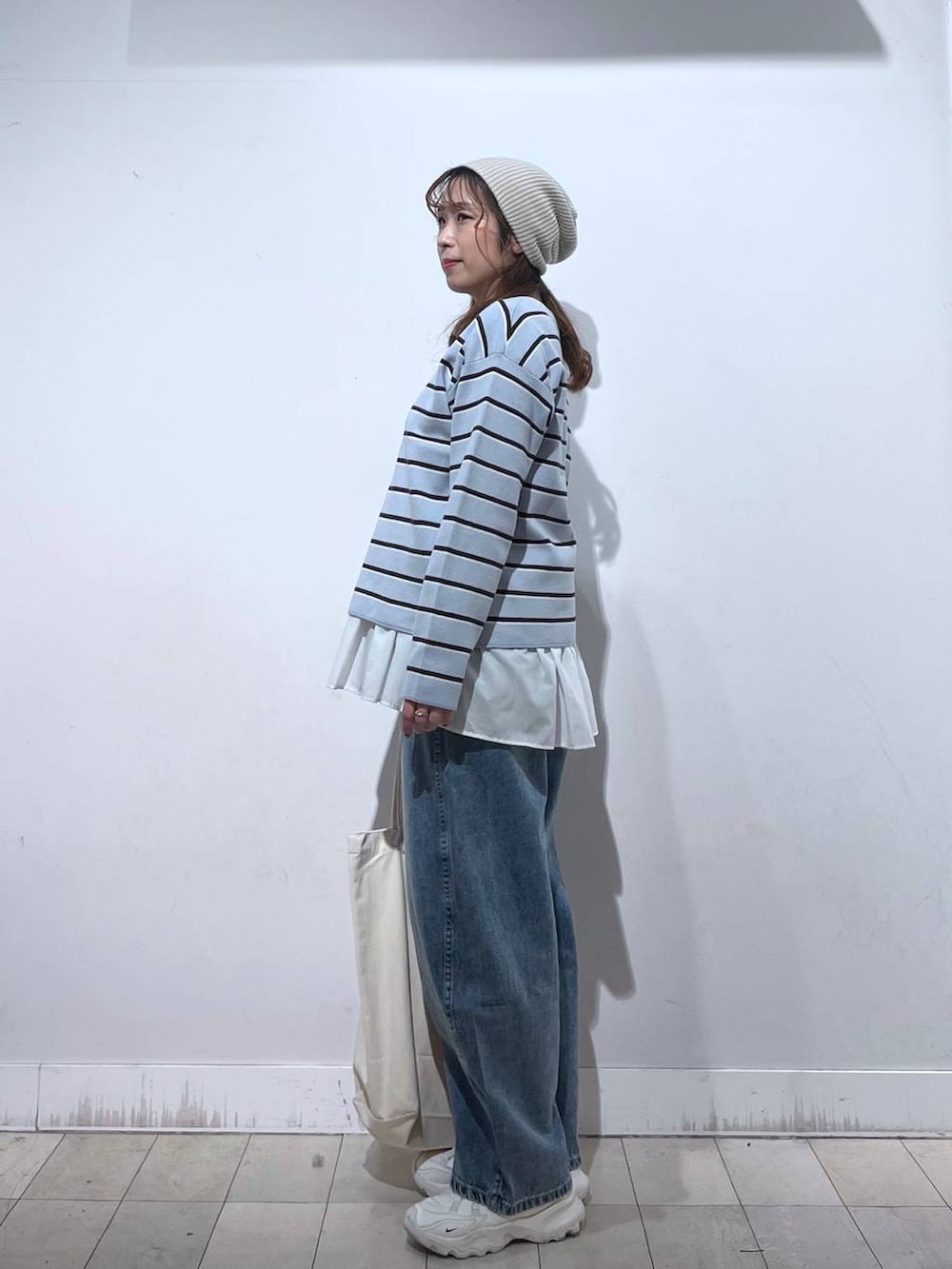 ホワイト系のTシャツ/カットソー、ホワイト系のトートバッグ、ブルー系のニット/セーターを着用したレディースの冬コーディネートの2枚目の写真