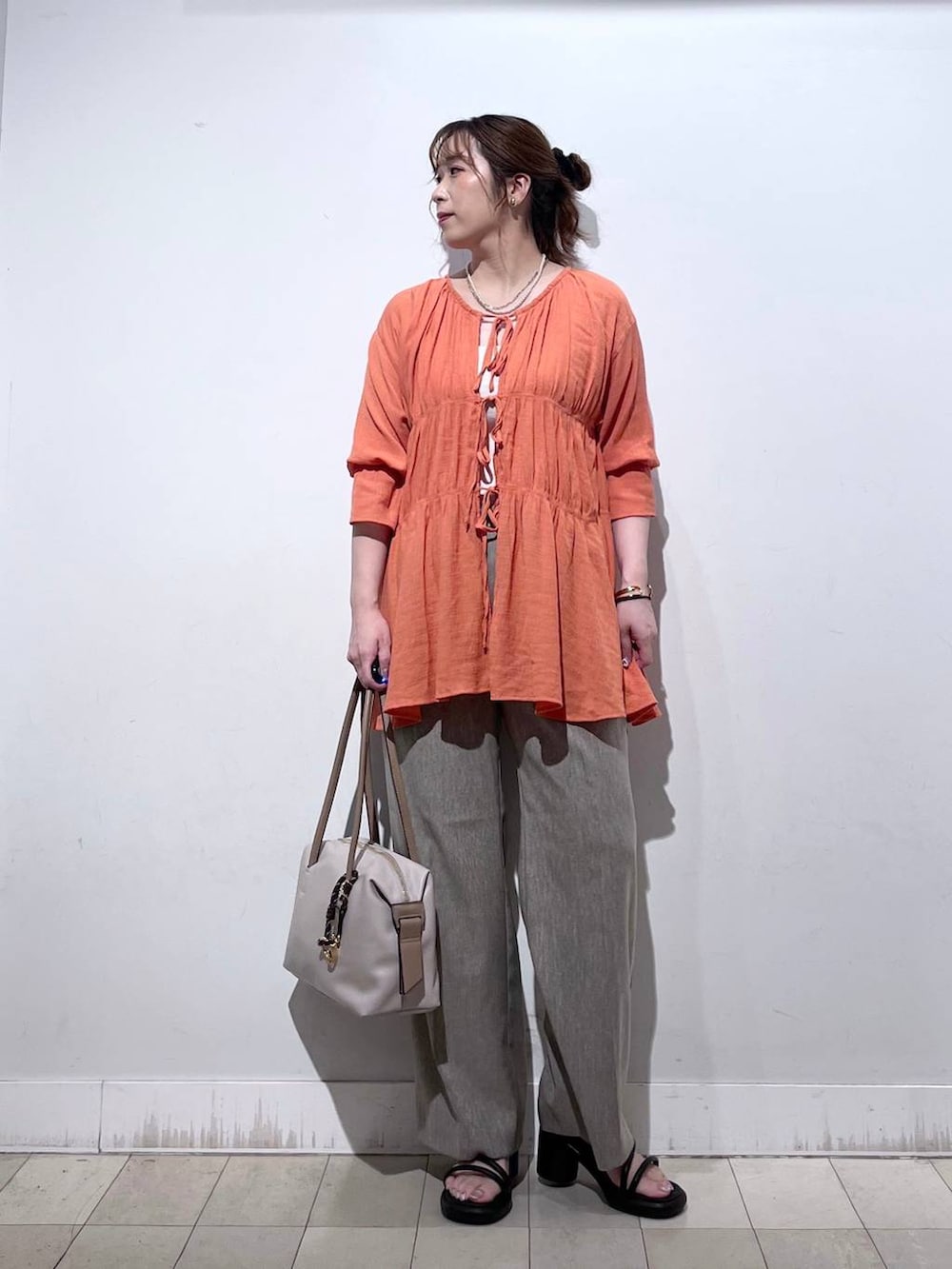 オレンジ系のシャツ/ブラウス、ホワイト系のタンクトップ、ベージュ系のボストンバッグを着用したレディースの秋コーディネートの7枚目の写真