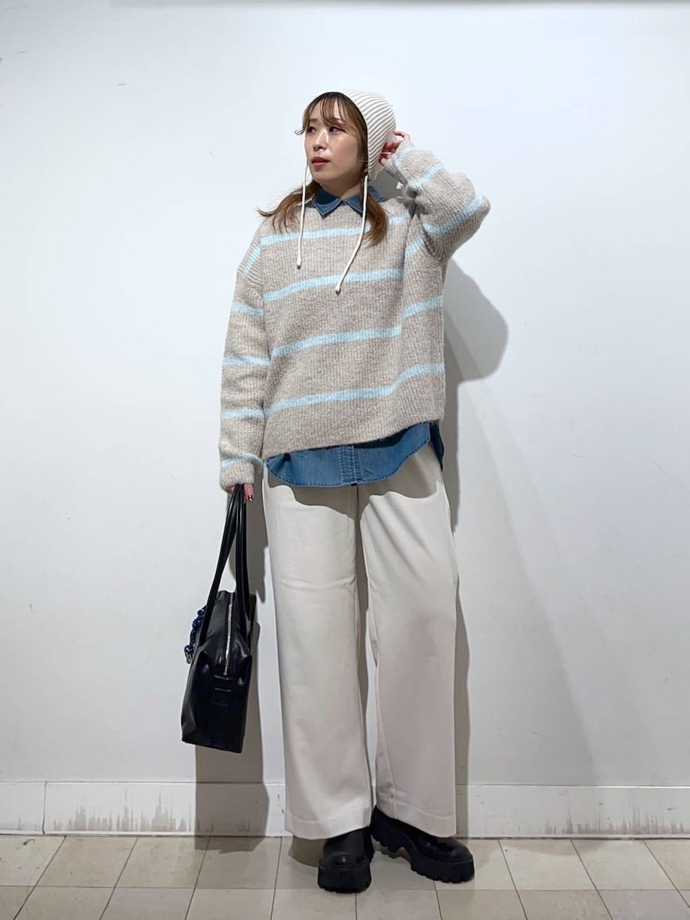 ブラック系のボストンバッグ、ブルー系のシャツ/ブラウス、ベージュ系のニット/セーターを着用したレディースの冬コーディネートの4枚目の写真