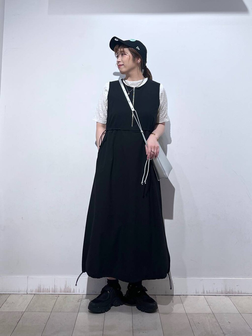 ブラック系のスニーカー、シルバー系のショルダーバッグ、ベージュ系のTシャツ/カットソーを着用したレディースの夏コーディネートの6枚目の写真