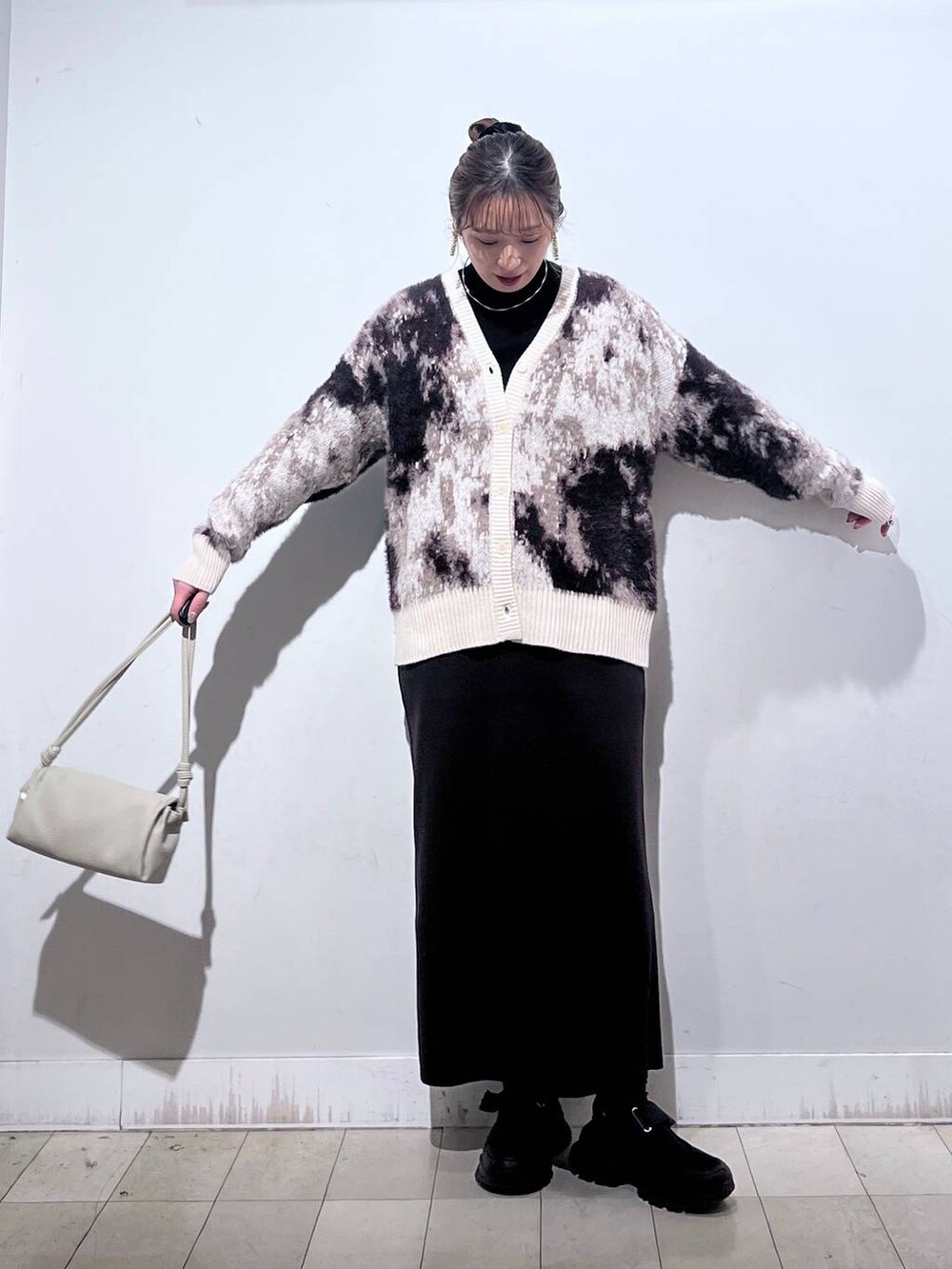 ブラック系のスニーカー、ブラック系のニット/セーター、ベージュ系のショルダーバッグを着用したレディースの秋コーディネートの2枚目の写真