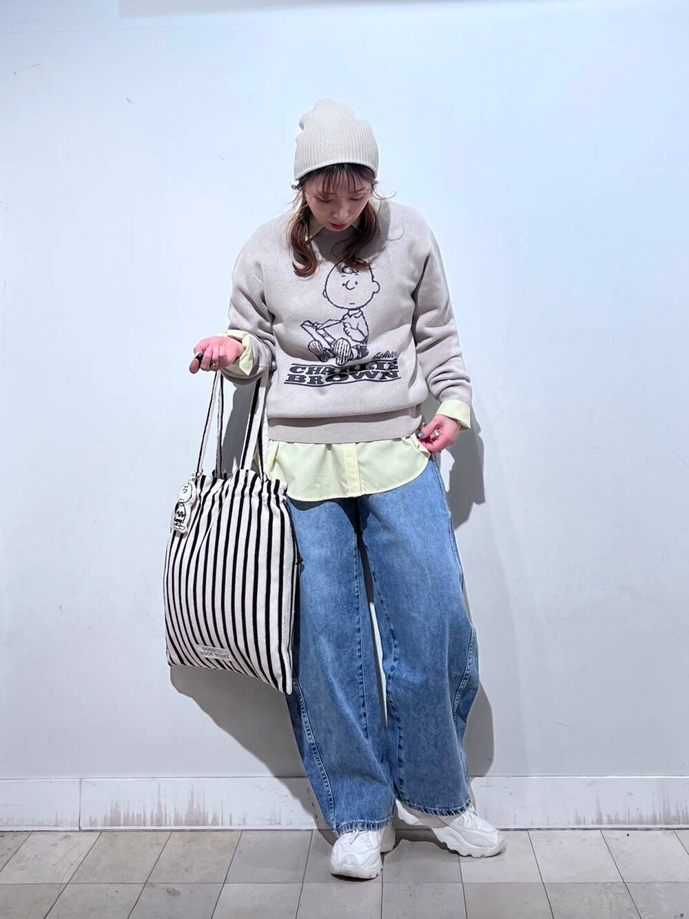 イエロー系のシャツ/ブラウス、ブルー系のデニムパンツ、ベージュ系のニット/セーターを着用したレディースの冬コーディネートの2枚目の写真