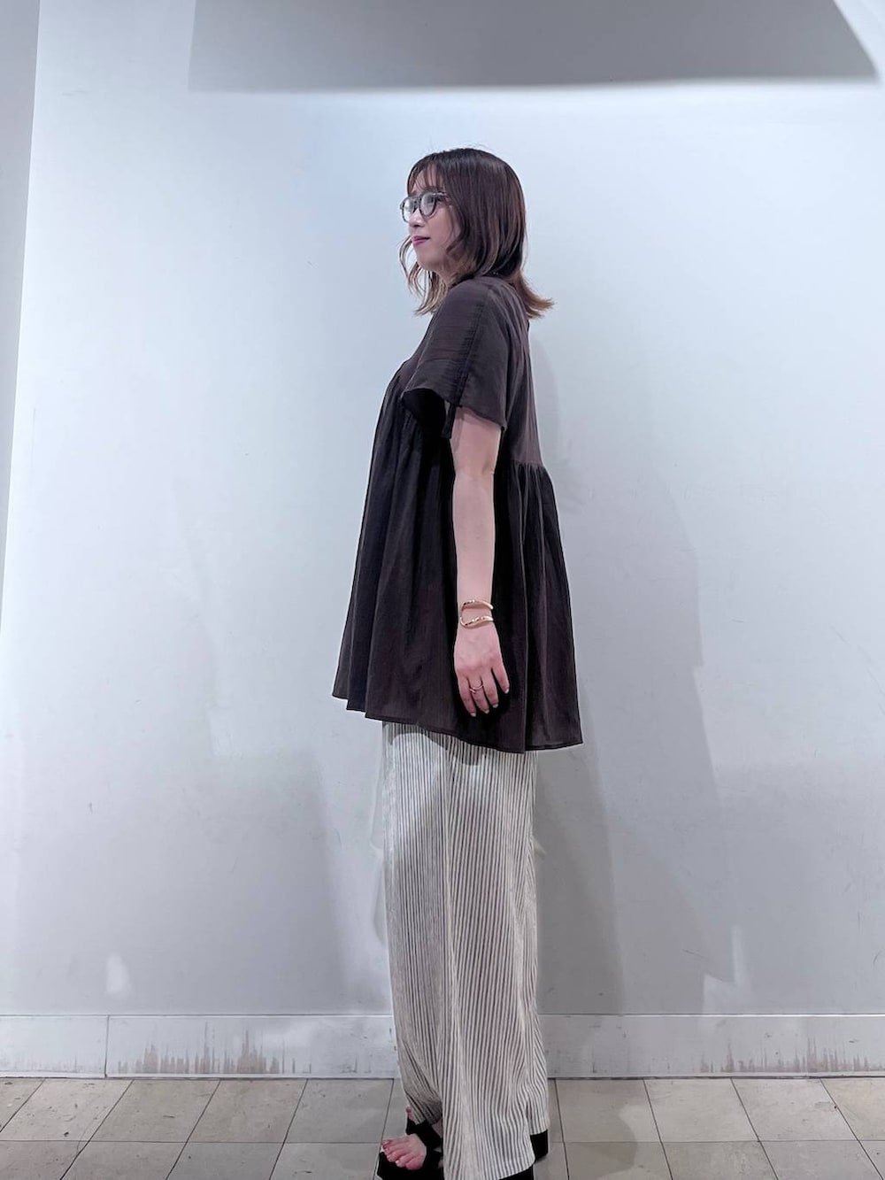 ベージュ系のショルダーバッグ、ベージュ系のその他パンツ、ブラウン系のシャツ/ブラウスを着用したレディースの夏コーディネートの2枚目の写真