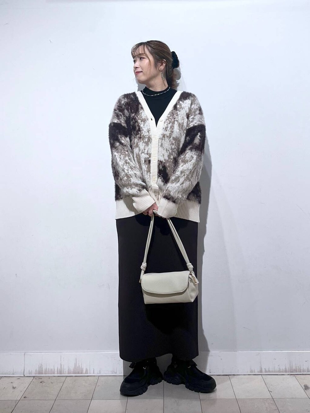 ブラック系のスニーカー、ブラック系のニット/セーター、ベージュ系のショルダーバッグを着用したレディースの秋コーディネートの4枚目の写真