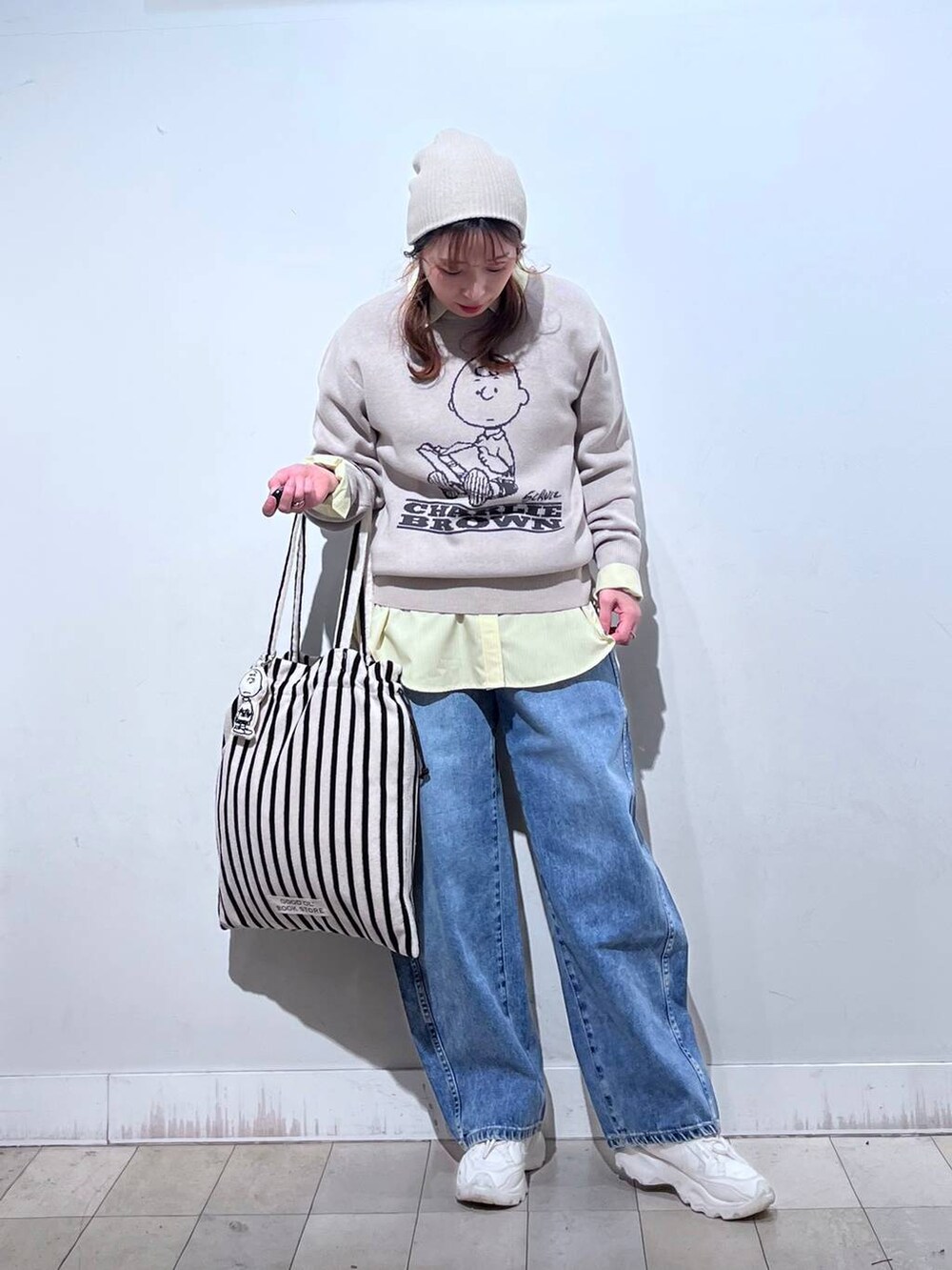 イエロー系のシャツ/ブラウス、ブルー系のデニムパンツ、ベージュ系のニット/セーターを着用したレディースの冬コーディネートの7枚目の写真