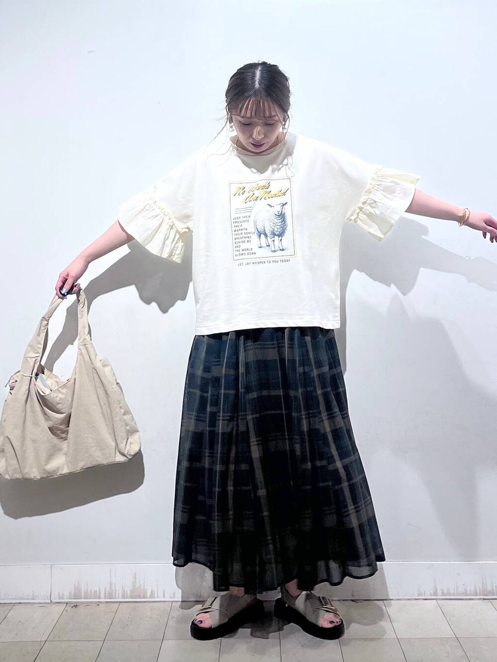 ホワイト系のタンクトップ、ベージュ系のトートバッグ、ベージュ系のサンダルを着用したレディースの秋コーディネートの4枚目の写真