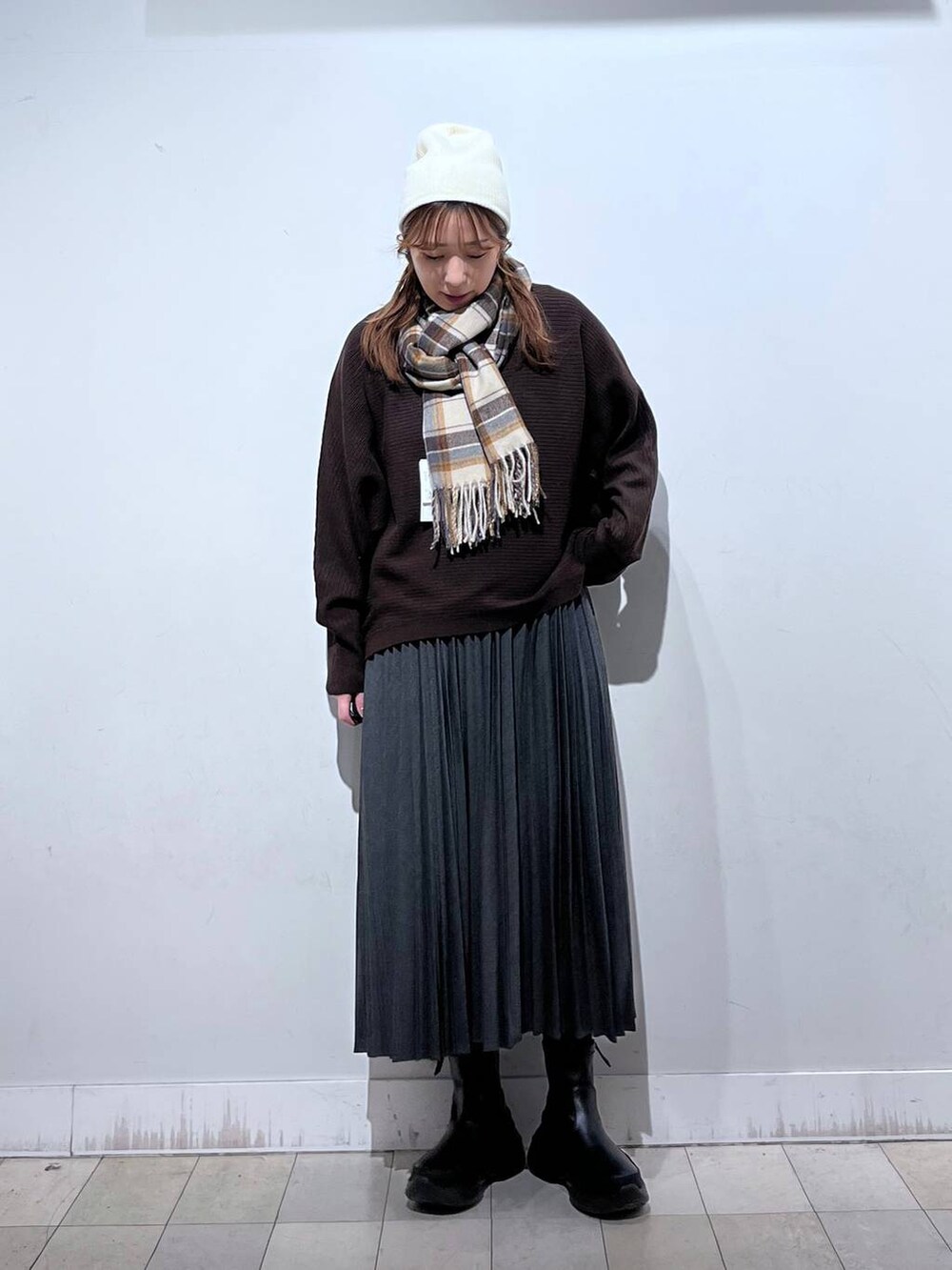 ブラック系のブーツ、グレー系のスカート、ブラウン系のマフラーを着用したレディースの冬コーディネートの5枚目の写真