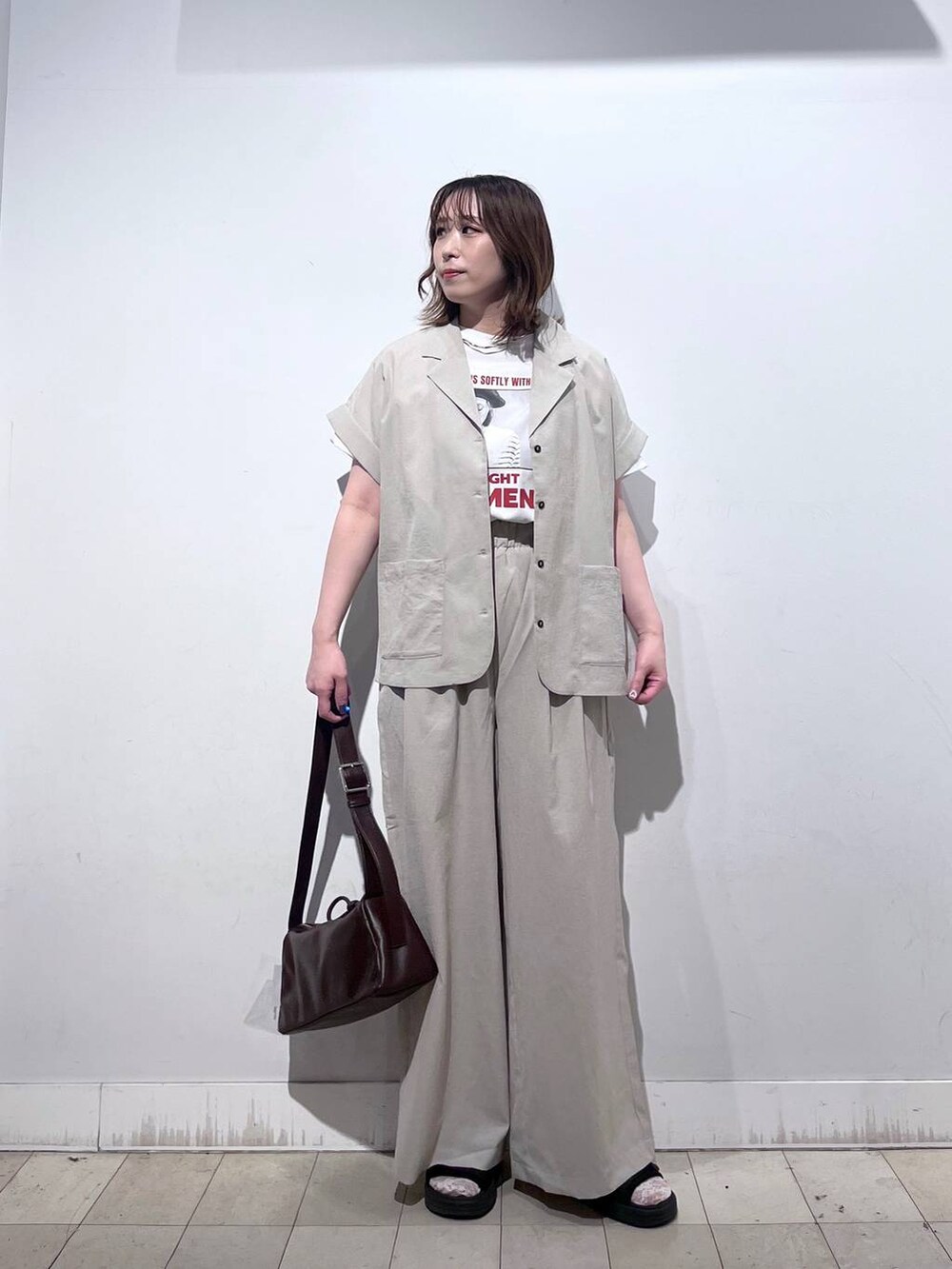 ブラウン系のショルダーバッグ、ホワイト系のTシャツ/カットソー、ブラック系のサンダルを着用したレディースの春コーディネートの3枚目の写真