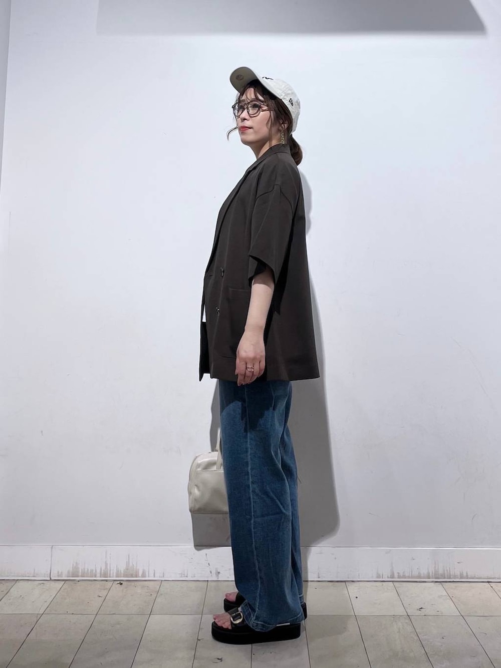 ブルー系のデニムパンツ、ホワイト系のTシャツ/カットソー、ベージュ系のショルダーバッグを着用したレディースの春コーディネートの4枚目の写真