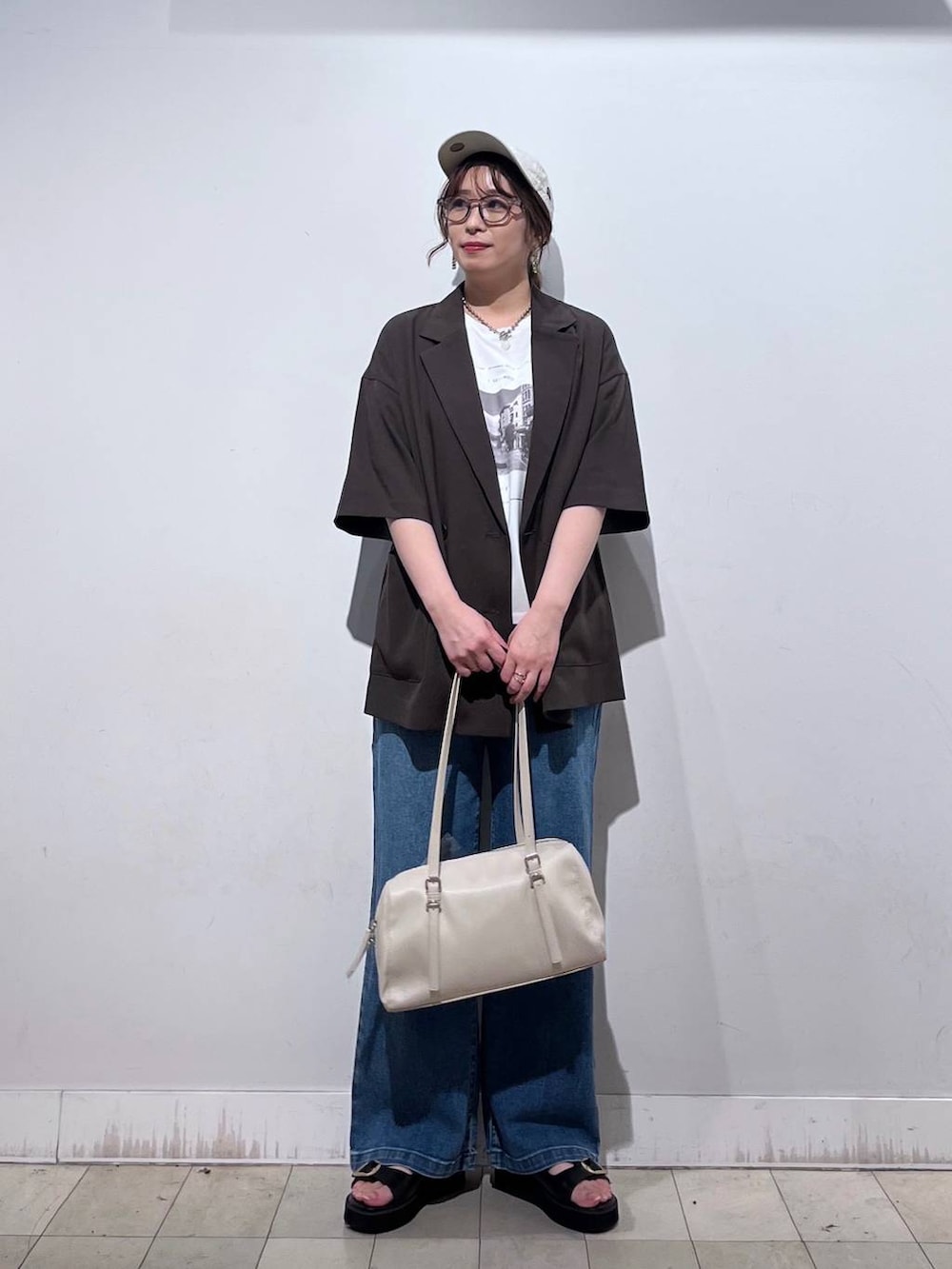 ブルー系のデニムパンツ、ホワイト系のTシャツ/カットソー、ベージュ系のショルダーバッグを着用したレディースの春コーディネートの2枚目の写真