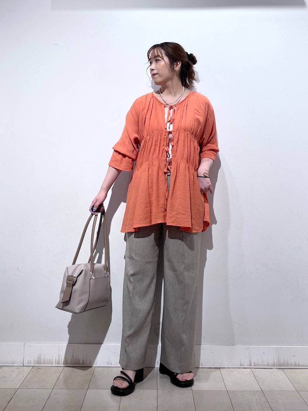 オレンジ系のシャツ/ブラウス、ホワイト系のタンクトップ、ベージュ系のボストンバッグを着用したレディースの秋コーディネートの8枚目の写真