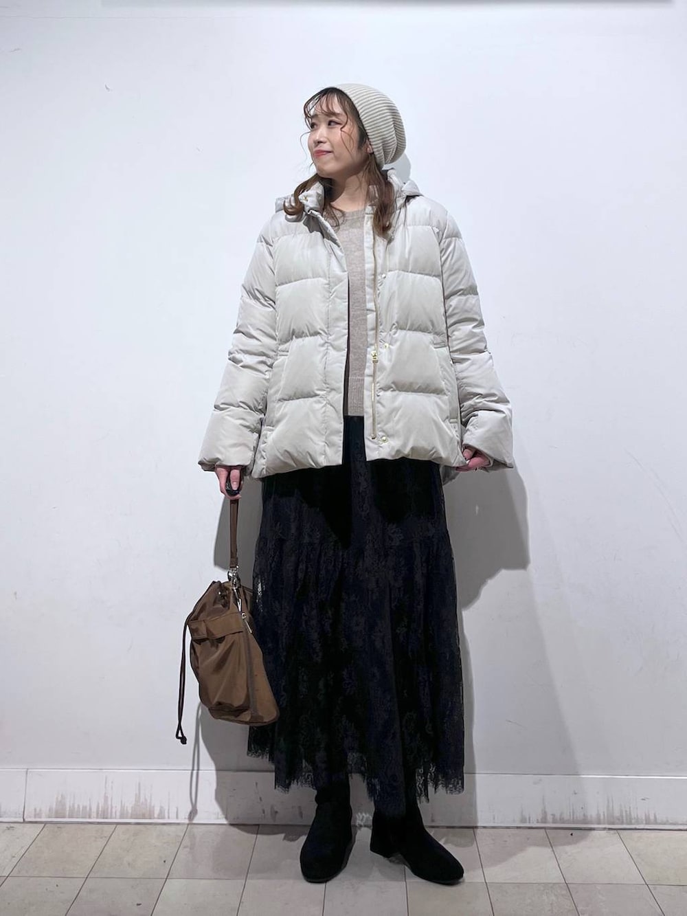 ブラウン系のショルダーバッグ、ベージュ系のダウンジャケット/コート、イエロー系のワンピースを着用したレディースの冬コーディネートの7枚目の写真