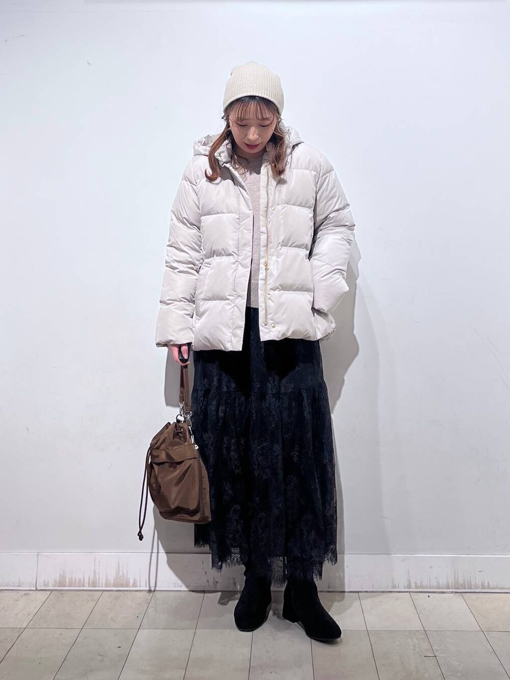 ブラウン系のショルダーバッグ、ベージュ系のダウンジャケット/コート、イエロー系のワンピースを着用したレディースの冬コーディネートの5枚目の写真