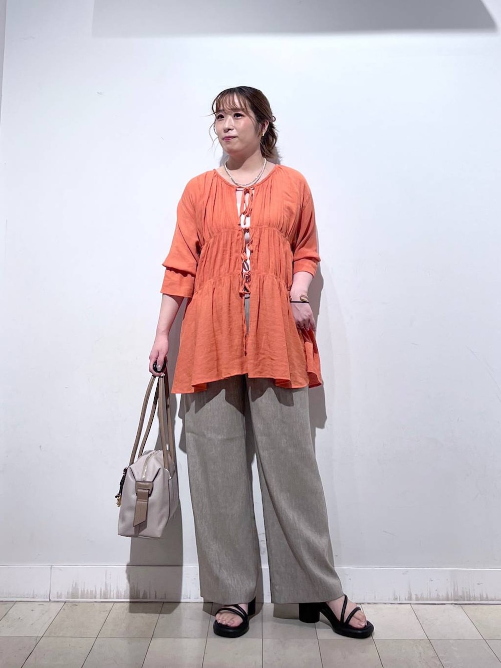 オレンジ系のシャツ/ブラウス、ホワイト系のタンクトップ、ベージュ系のボストンバッグを着用したレディースの秋コーディネートの4枚目の写真