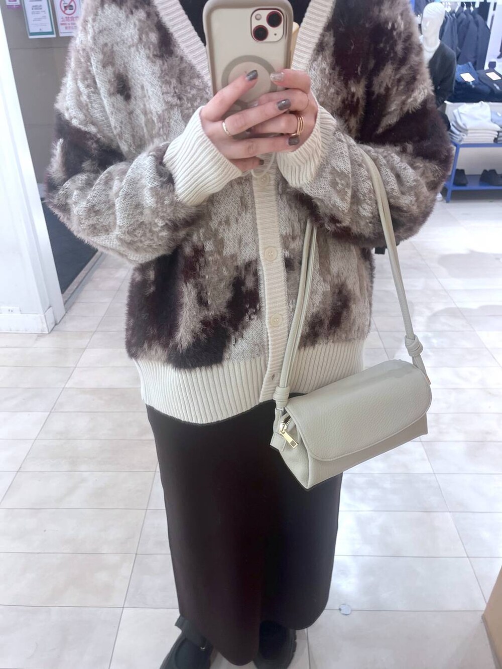 ブラック系のスニーカー、ブラック系のニット/セーター、ベージュ系のショルダーバッグを着用したレディースの秋コーディネートの3枚目の写真