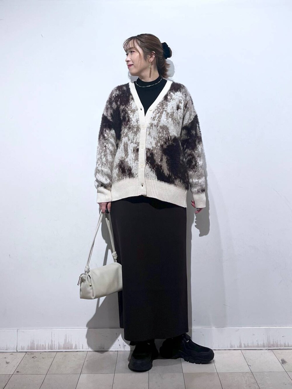 ブラック系のスニーカー、ブラック系のニット/セーター、ベージュ系のショルダーバッグを着用したレディースの秋コーディネートの7枚目の写真