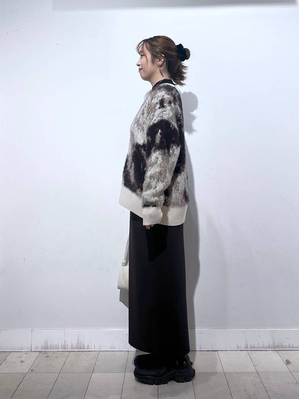 ブラック系のスニーカー、ブラック系のニット/セーター、ベージュ系のショルダーバッグを着用したレディースの秋コーディネートの6枚目の写真