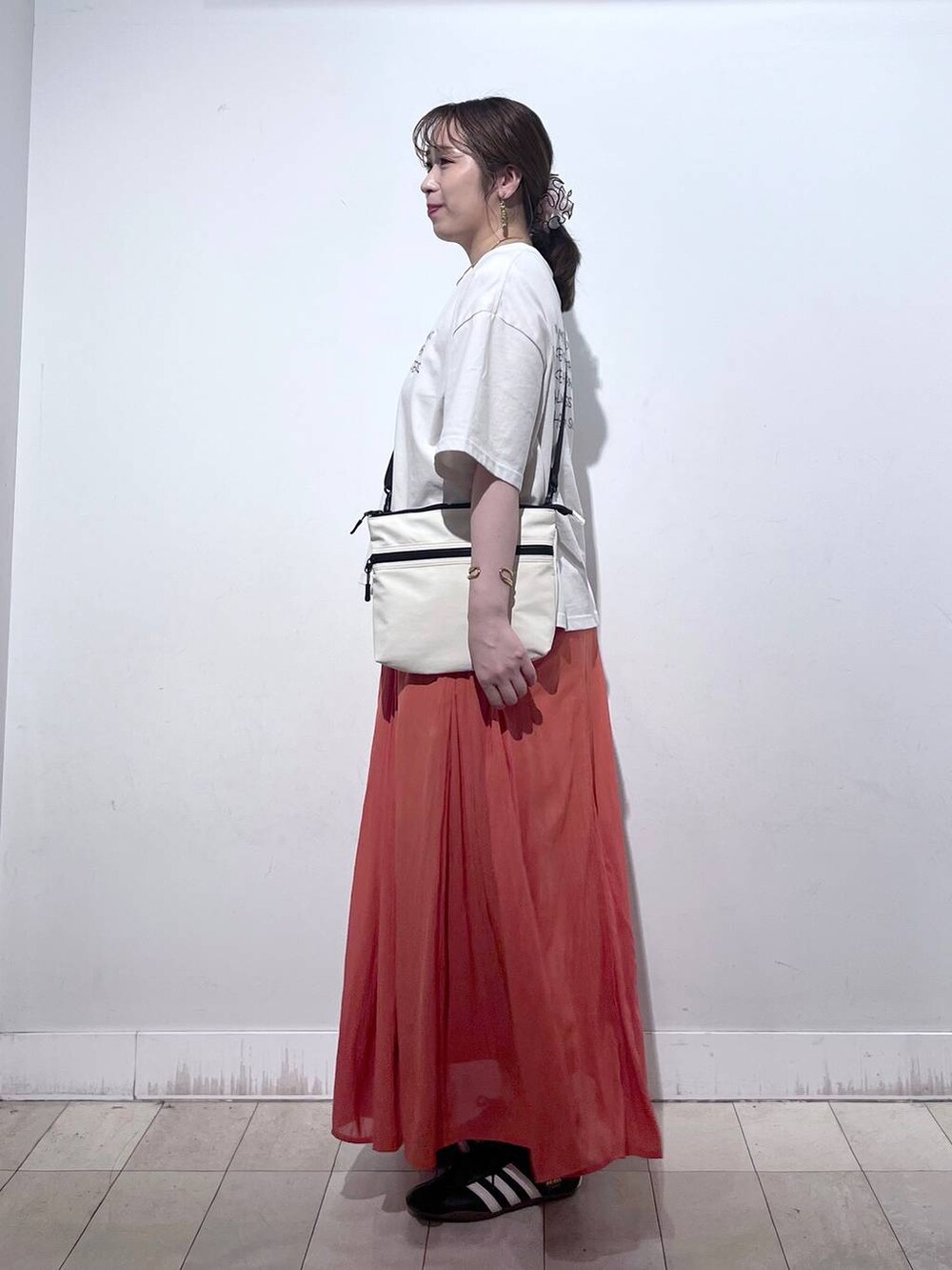 オレンジ系のスカート、ベージュ系のTシャツ/カットソー、ホワイト系のタンクトップを着用したレディースの夏コーディネートの6枚目の写真
