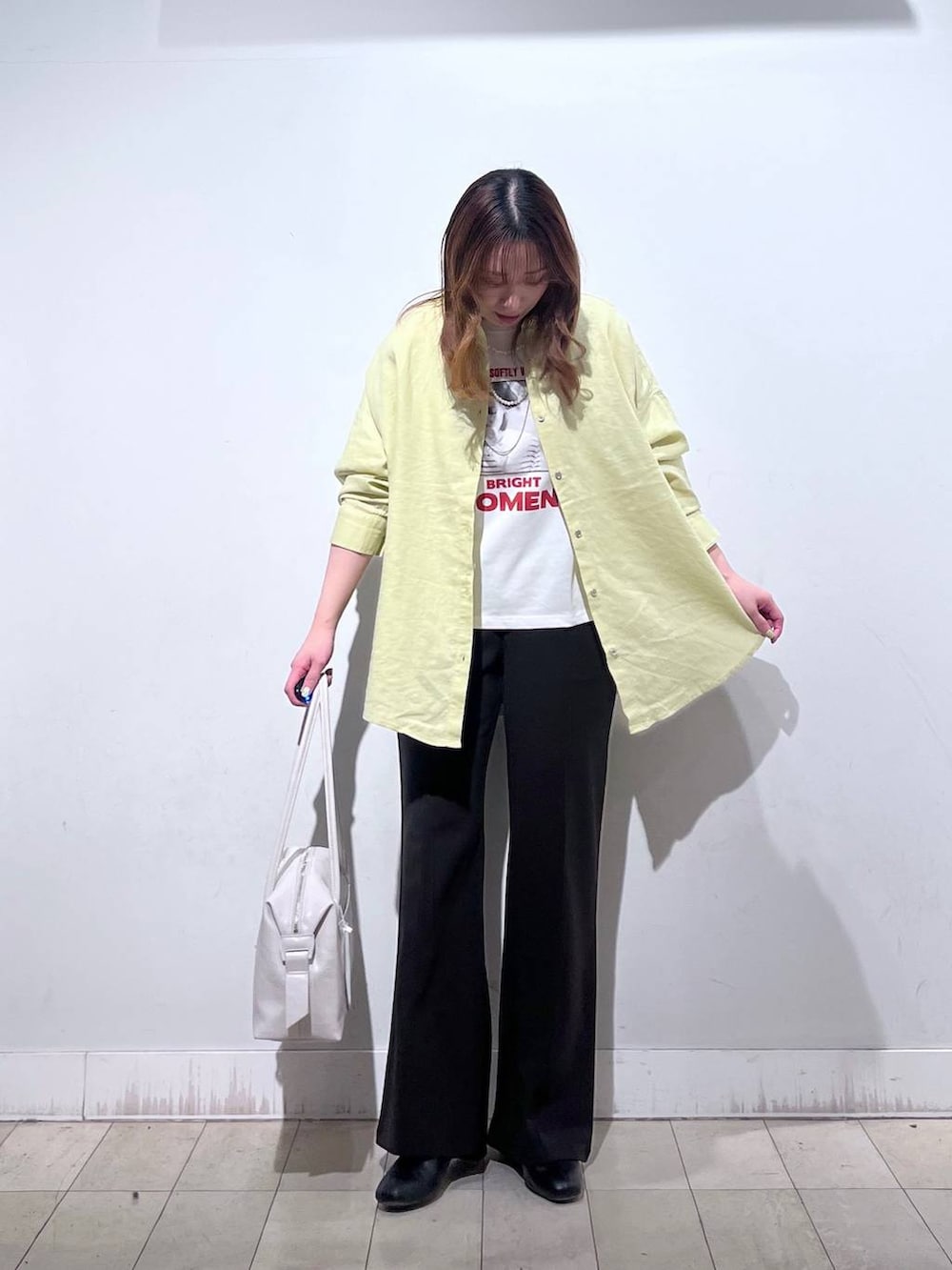 ホワイト系のボストンバッグ、ブラック系のブーツ、イエロー系のシャツ/ブラウスを着用したレディースの春コーディネートの3枚目の写真