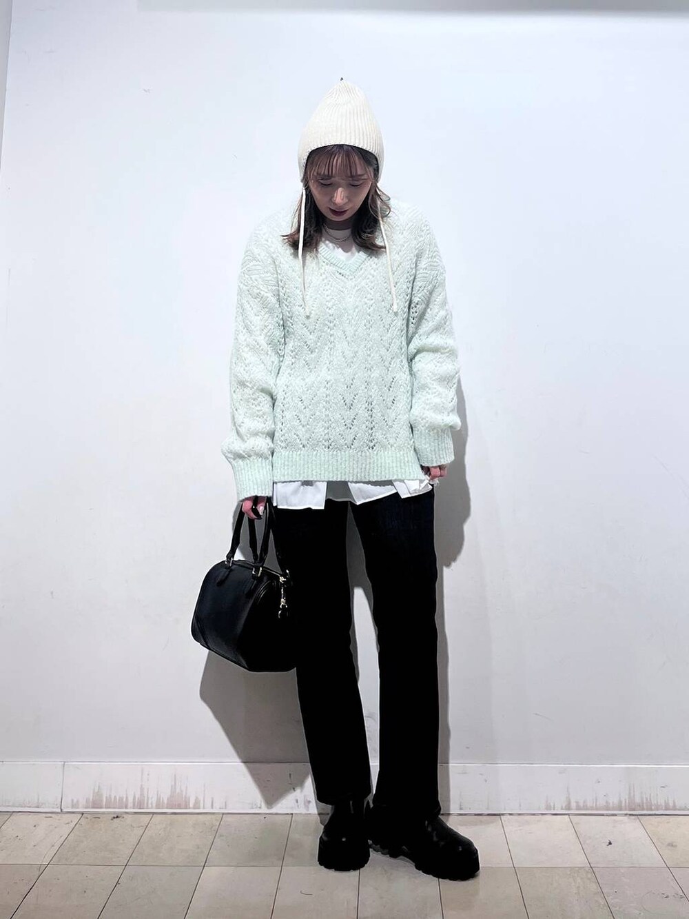 ブラック系のデニムパンツ、ホワイト系のTシャツ/カットソー、ブラック系のボストンバッグを着用したレディースの秋コーディネートの3枚目の写真