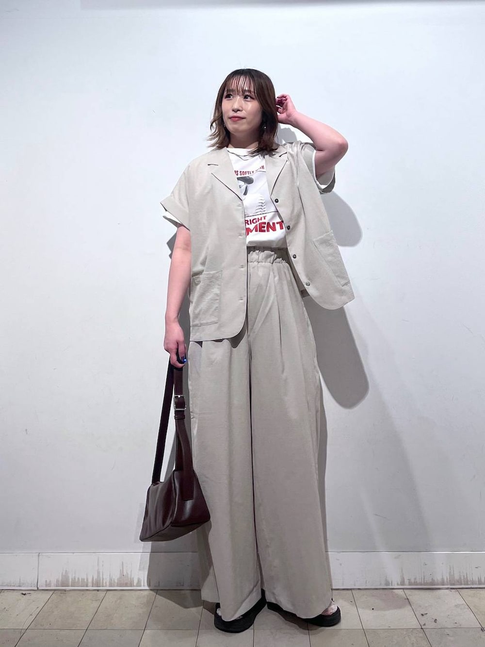 ブラウン系のショルダーバッグ、ホワイト系のTシャツ/カットソー、ブラック系のサンダルを着用したレディースの春コーディネートの7枚目の写真