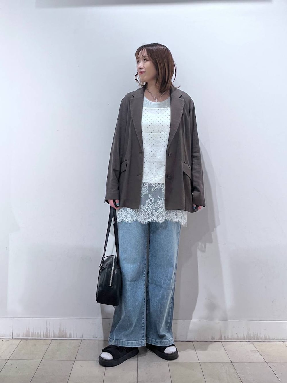 ブルー系のデニムパンツ、ブラウン系のテーラードジャケット、ホワイト系のキャミソールを着用したレディースの夏コーディネートの8枚目の写真