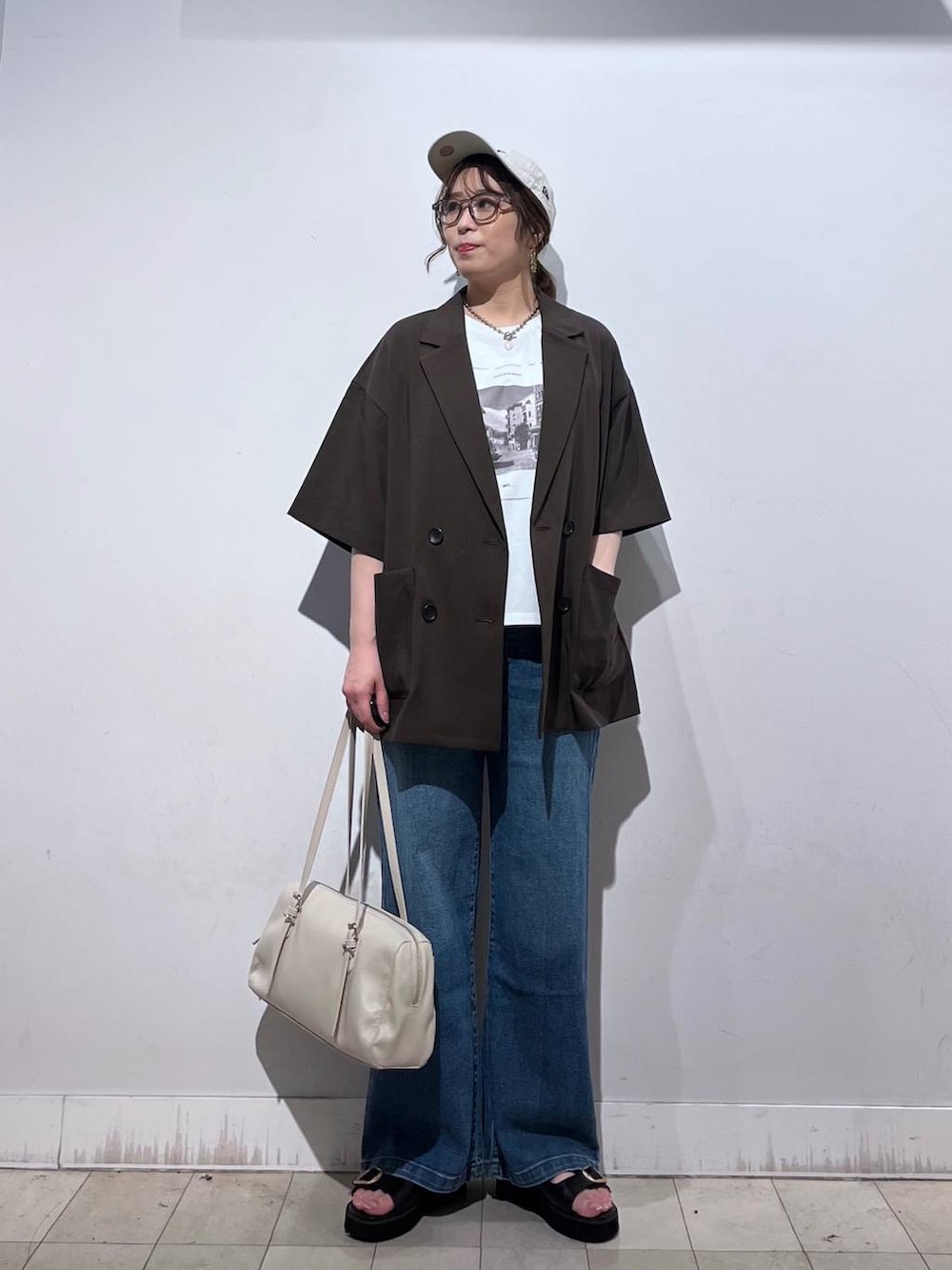 ブルー系のデニムパンツ、ホワイト系のTシャツ/カットソー、ベージュ系のショルダーバッグを着用したレディースの春コーディネートの6枚目の写真