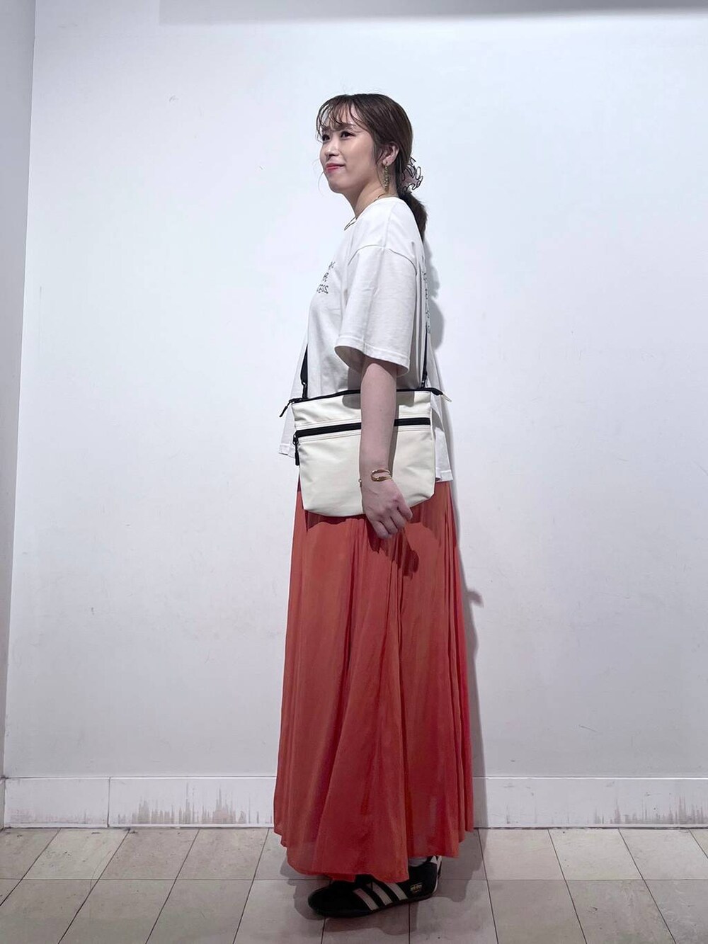 オレンジ系のスカート、ベージュ系のTシャツ/カットソー、ホワイト系のタンクトップを着用したレディースの夏コーディネートの2枚目の写真