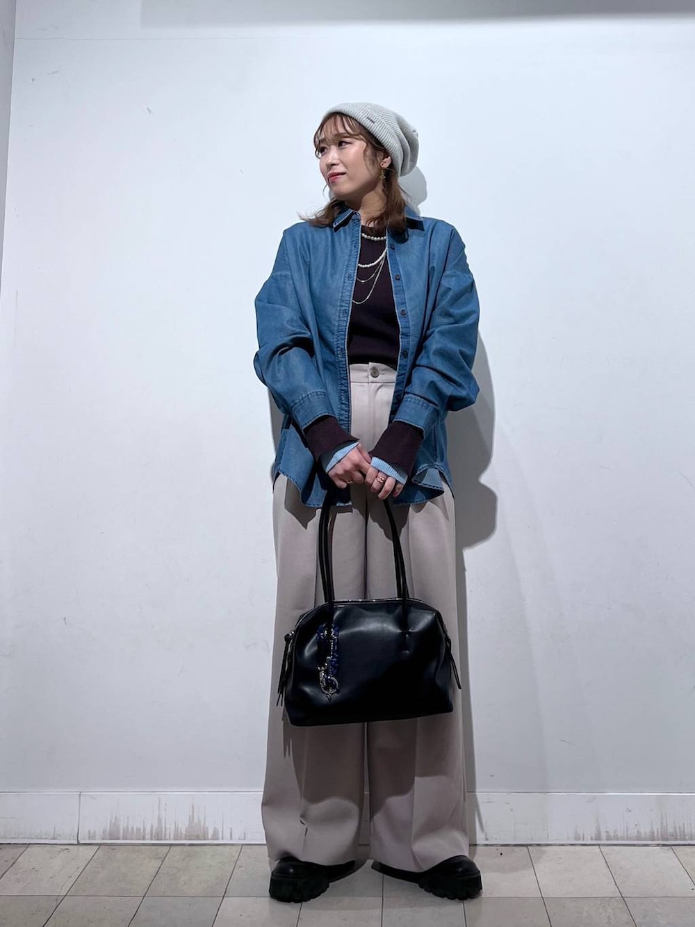 ブラック系のボストンバッグ、ブルー系のシャツ/ブラウス、ベージュ系のその他パンツを着用したレディースの冬コーディネートの6枚目の写真