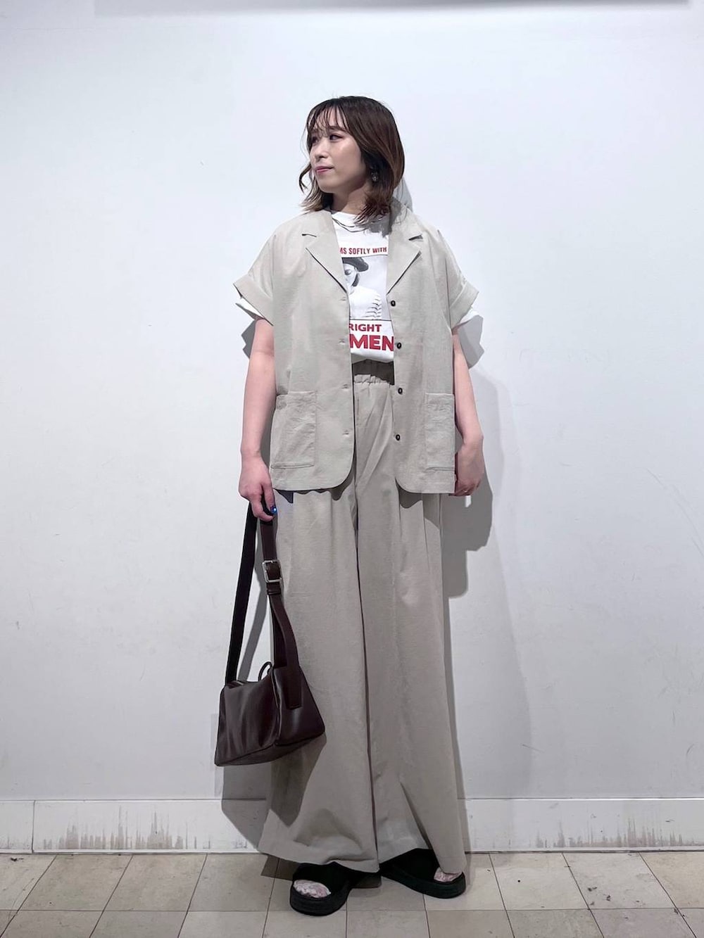 ブラウン系のショルダーバッグ、ベージュ系のその他パンツ、ホワイト系のTシャツ/カットソーを着用したレディースの夏コーディネートの4枚目の写真