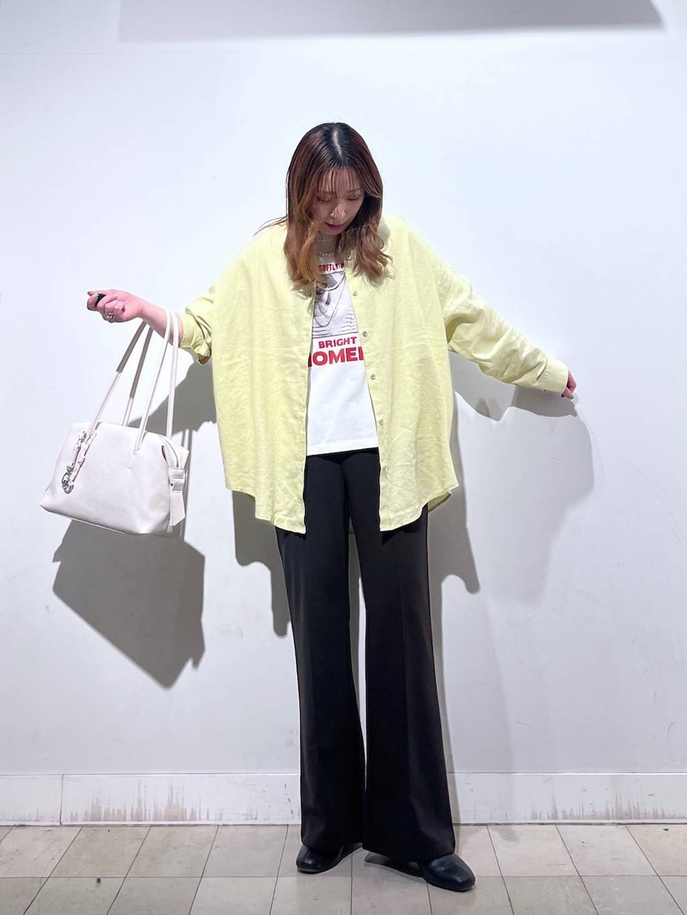 ホワイト系のボストンバッグ、ブラック系のブーツ、イエロー系のシャツ/ブラウスを着用したレディースの春コーディネートの4枚目の写真