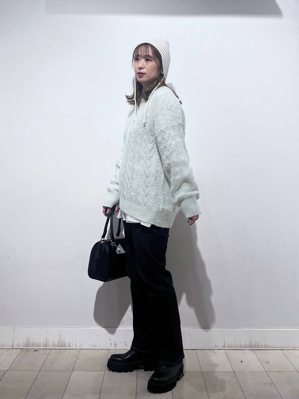 ブラック系のデニムパンツ、ホワイト系のTシャツ/カットソー、ブラック系のボストンバッグを着用したレディースの秋コーディネートの6枚目の写真