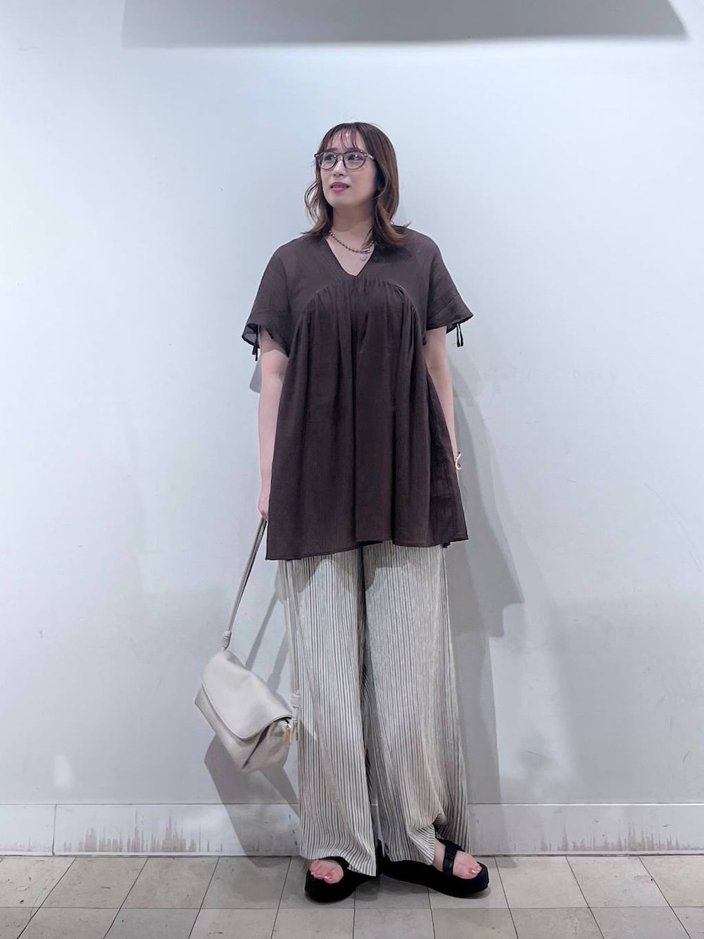 ベージュ系のショルダーバッグ、ベージュ系のその他パンツ、ブラウン系のシャツ/ブラウスを着用したレディースの夏コーディネートの7枚目の写真