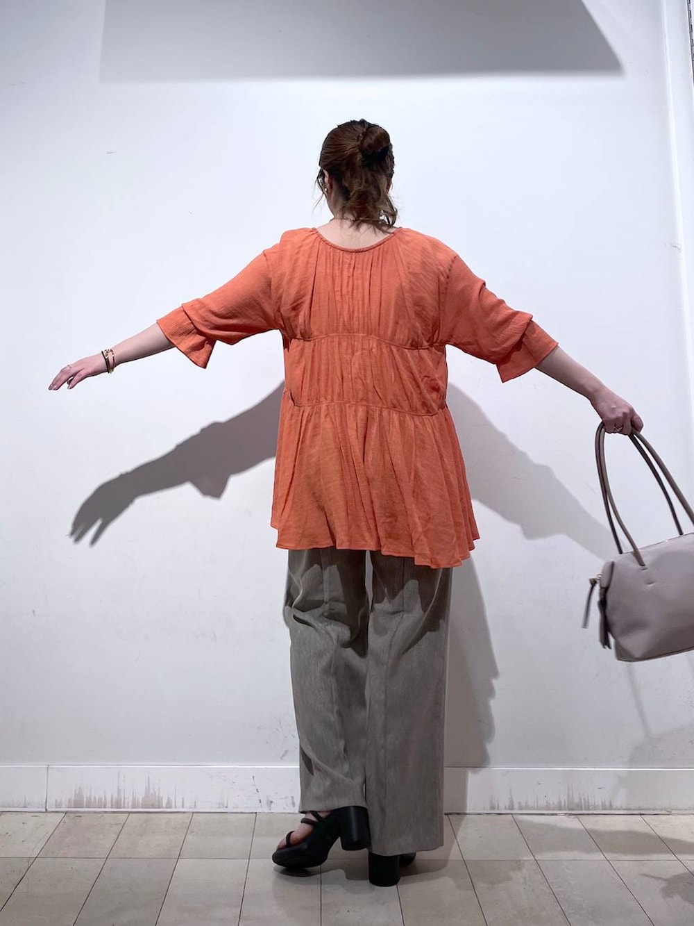 オレンジ系のシャツ/ブラウス、ホワイト系のタンクトップ、ベージュ系のボストンバッグを着用したレディースの秋コーディネートの9枚目の写真