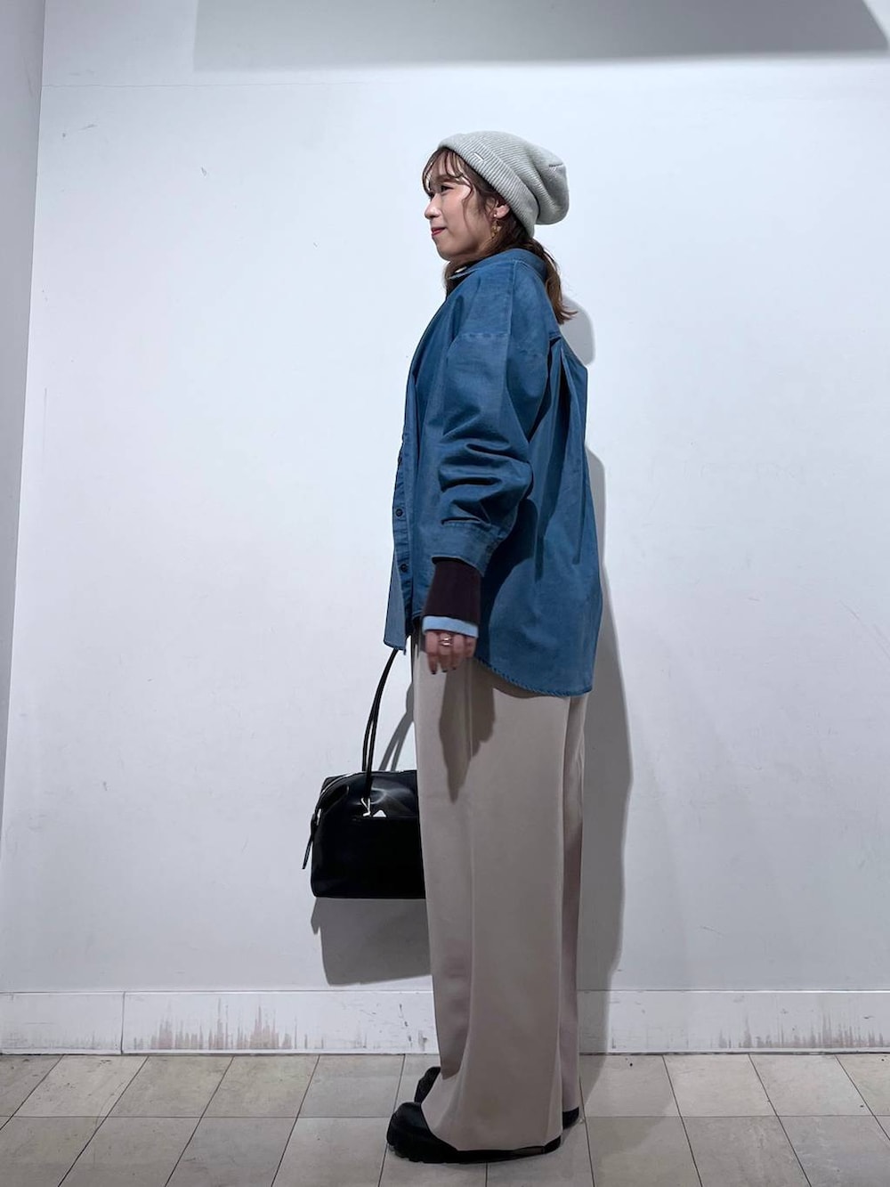 ブラック系のボストンバッグ、ブルー系のシャツ/ブラウス、ベージュ系のその他パンツを着用したレディースの冬コーディネートの3枚目の写真