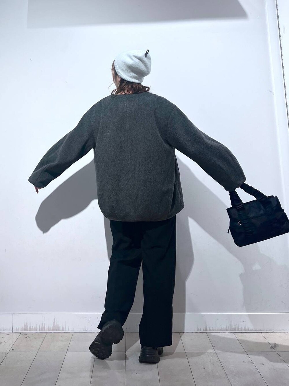 ブラック系のスニーカー、ブラック系のショルダーバッグ、グレー系のノーカラーコートを着用したレディースの秋コーディネートの6枚目の写真