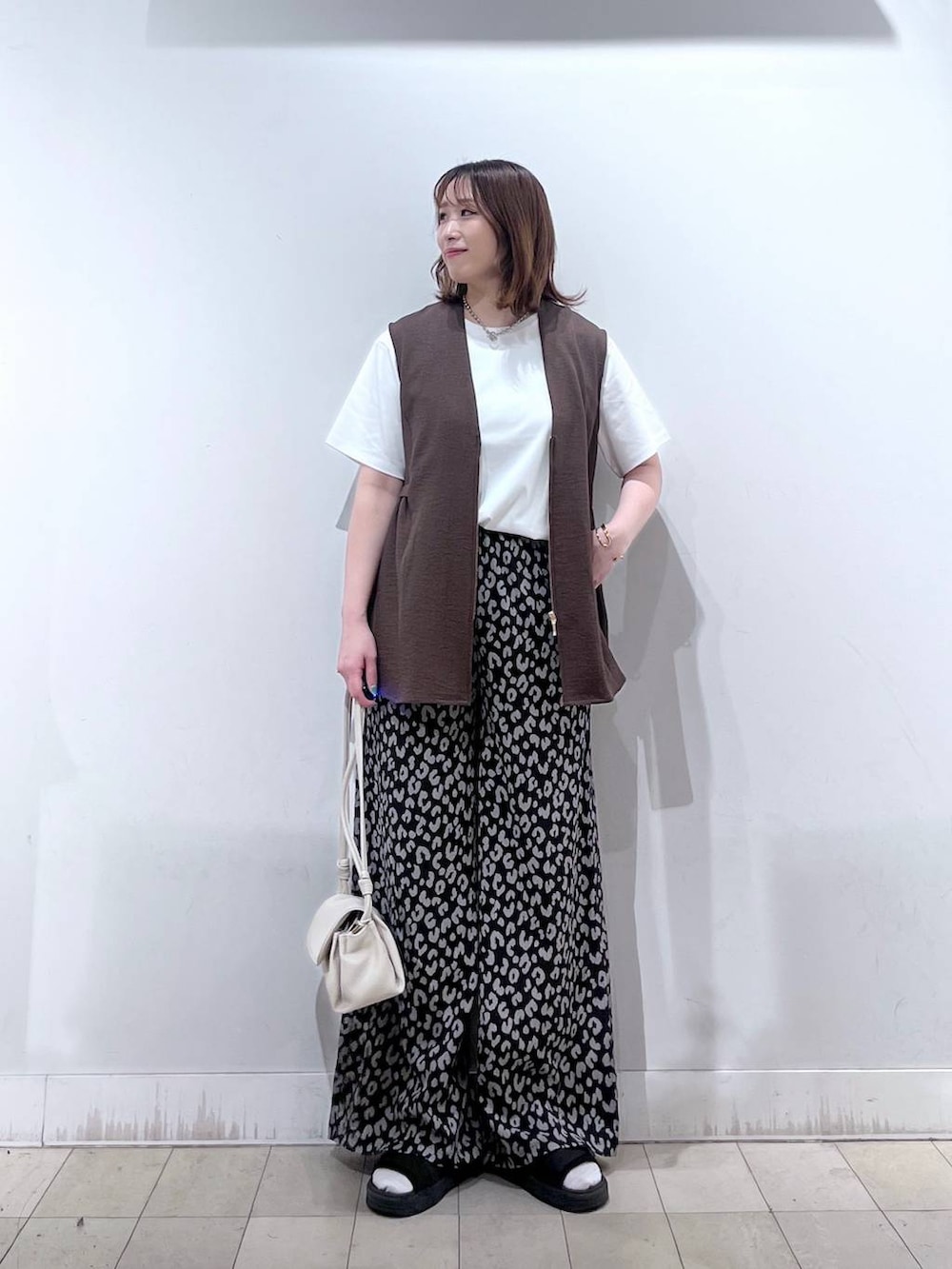 ベージュ系のショルダーバッグ、ブラウン系のベスト、その他のその他パンツを着用したレディースの夏コーディネートの6枚目の写真