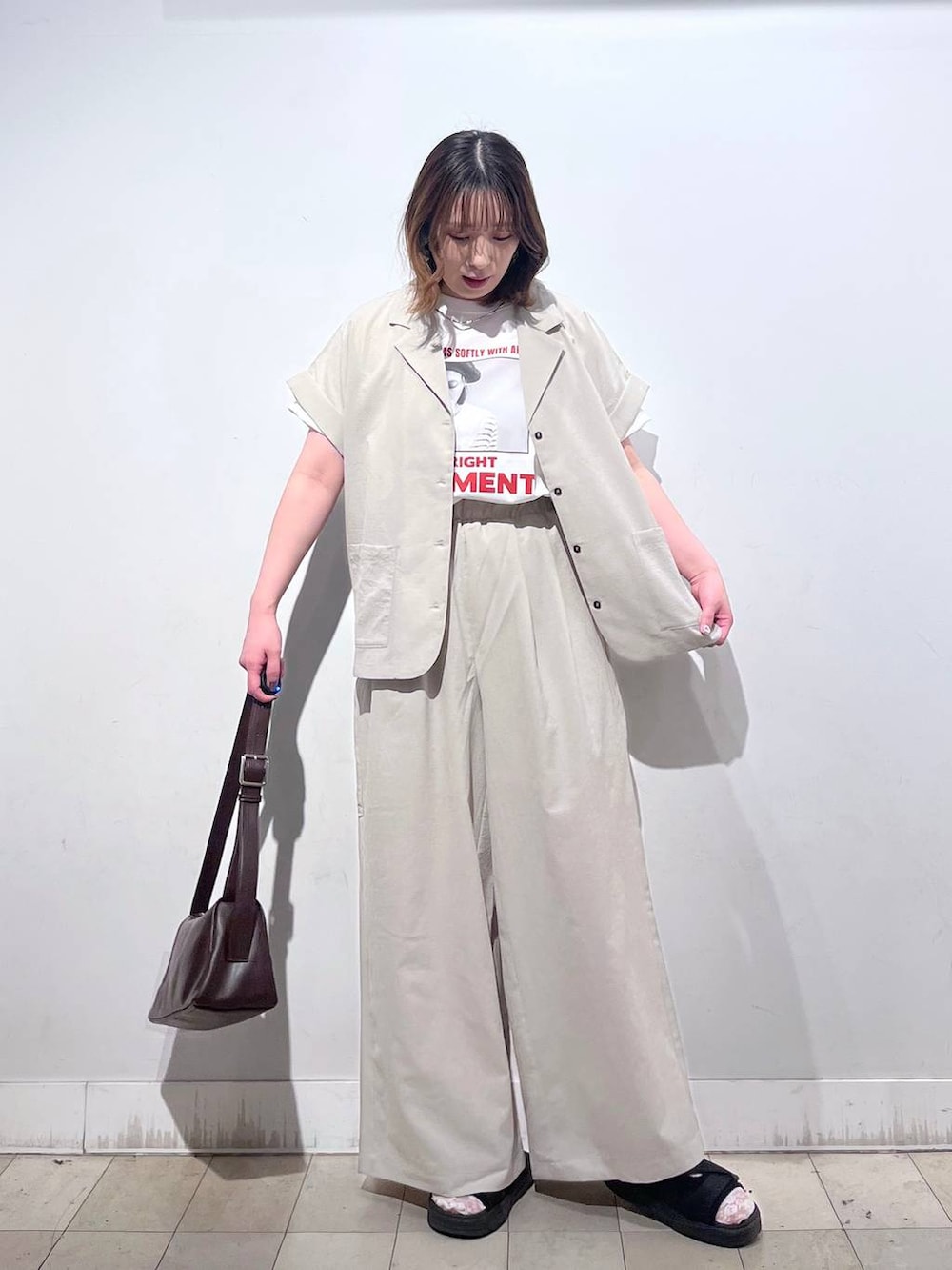 ブラウン系のショルダーバッグ、ベージュ系のその他パンツ、ホワイト系のTシャツ/カットソーを着用したレディースの夏コーディネートの3枚目の写真