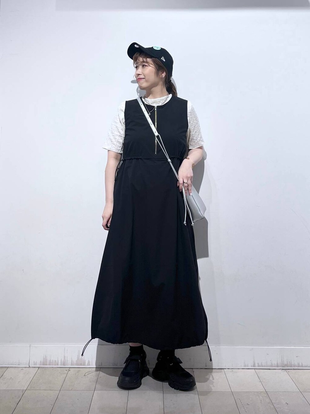 ブラック系のスニーカー、シルバー系のショルダーバッグ、ベージュ系のTシャツ/カットソーを着用したレディースの夏コーディネートの8枚目の写真