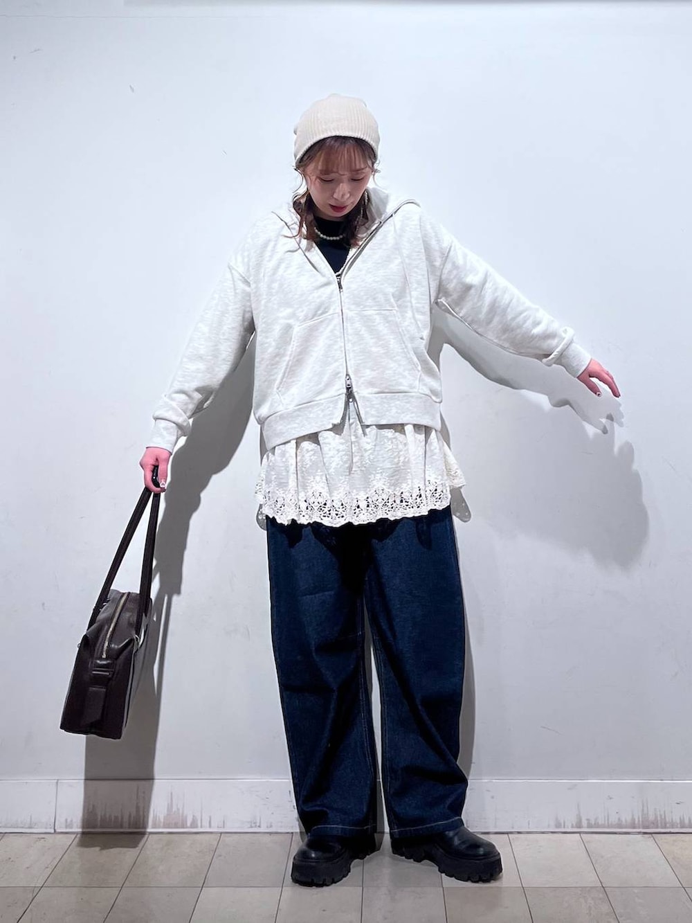 ブラウン系のボストンバッグ、ホワイト系のパーカー、ホワイト系のその他トップスを着用したレディースの冬コーディネートの3枚目の写真
