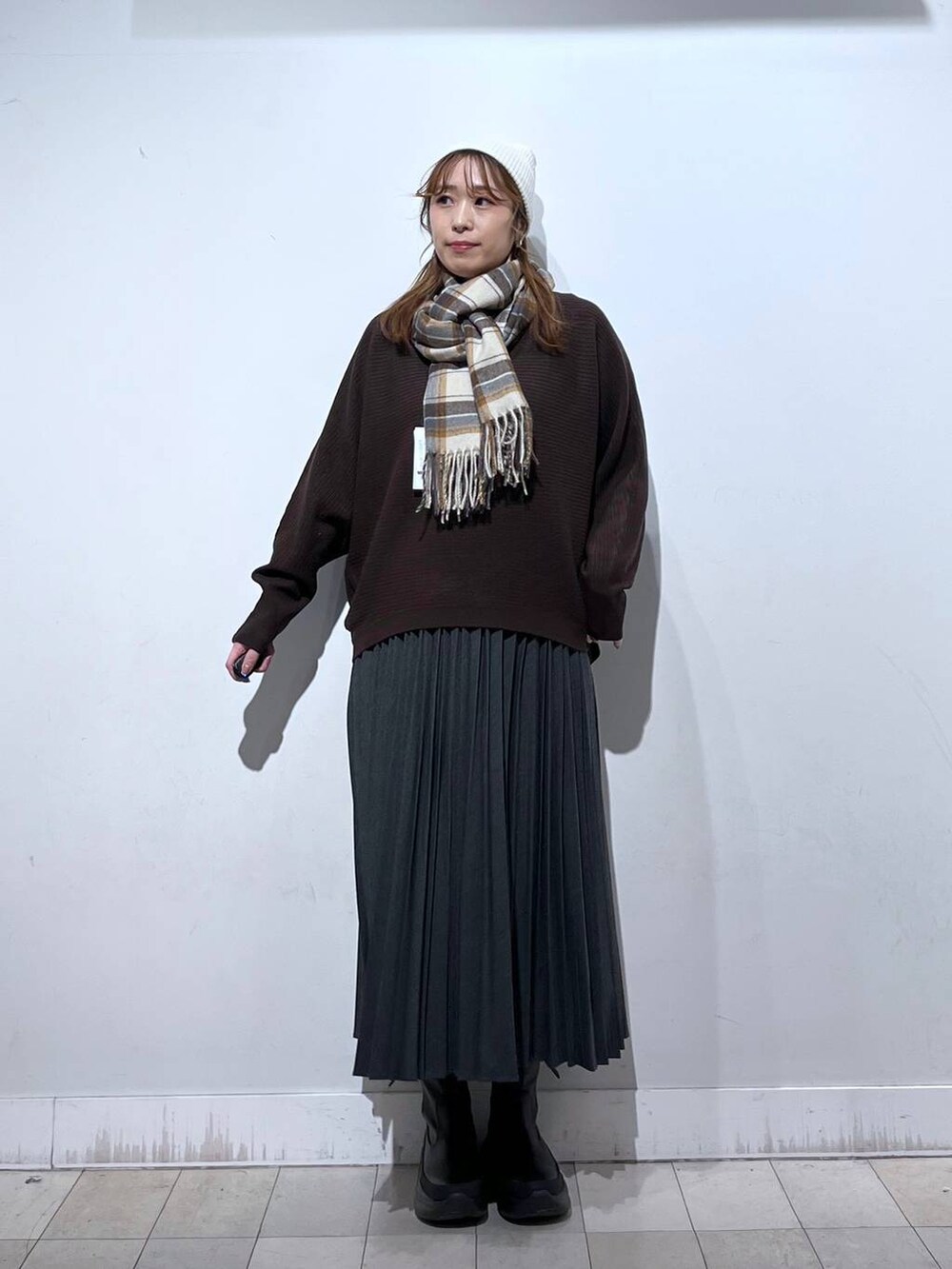 ブラック系のブーツ、グレー系のスカート、ブラウン系のマフラーを着用したレディースの冬コーディネートの2枚目の写真