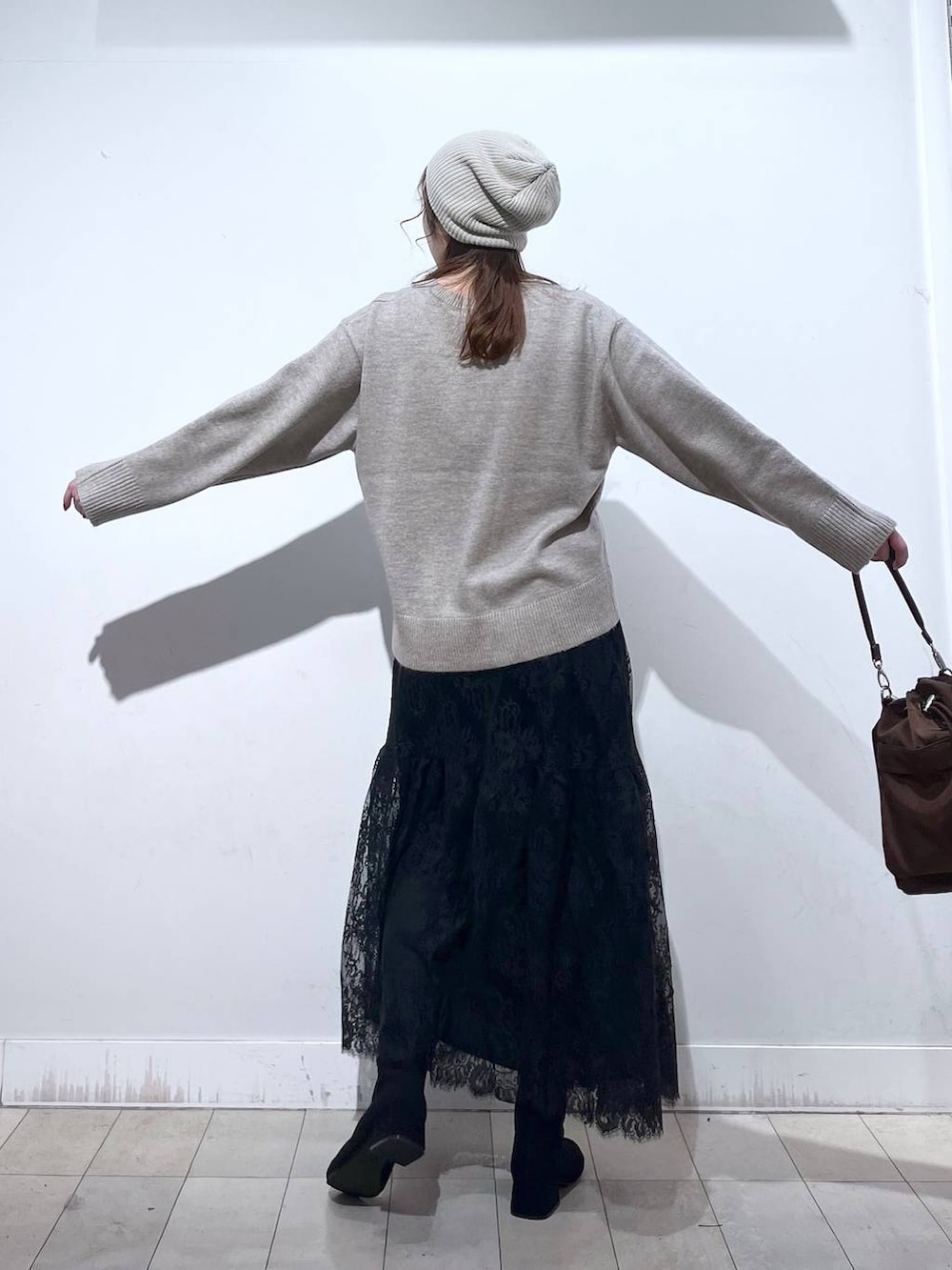 ブラウン系のショルダーバッグ、ベージュ系のダウンジャケット/コート、イエロー系のワンピースを着用したレディースの冬コーディネートの9枚目の写真