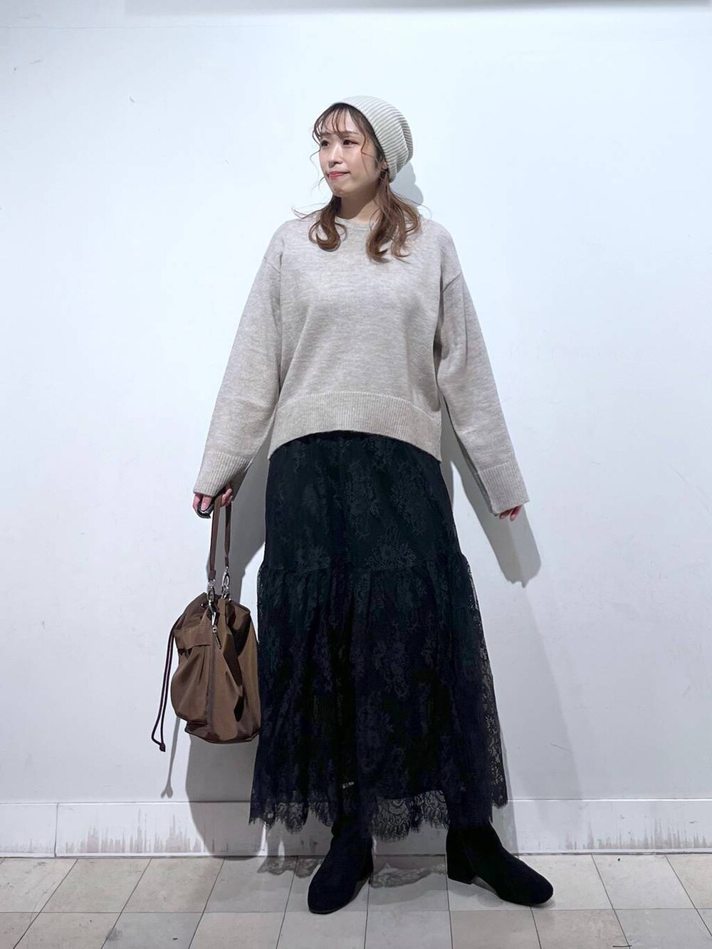 ブラウン系のショルダーバッグ、ベージュ系のダウンジャケット/コート、イエロー系のワンピースを着用したレディースの冬コーディネートの6枚目の写真