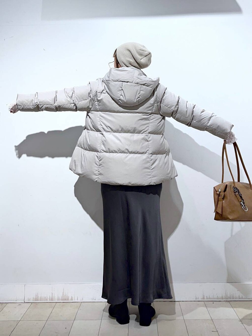 ブラウン系のボストンバッグ、ベージュ系のダウンジャケット/コート、ホワイト系のTシャツ/カットソーを着用したレディースの冬コーディネートの6枚目の写真