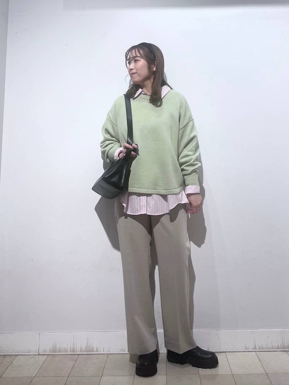 グリーン系のニット/セーター、ピンク系のシャツ/ブラウス、ベージュ系のスラックスを着用したレディースの春コーディネートの3枚目の写真