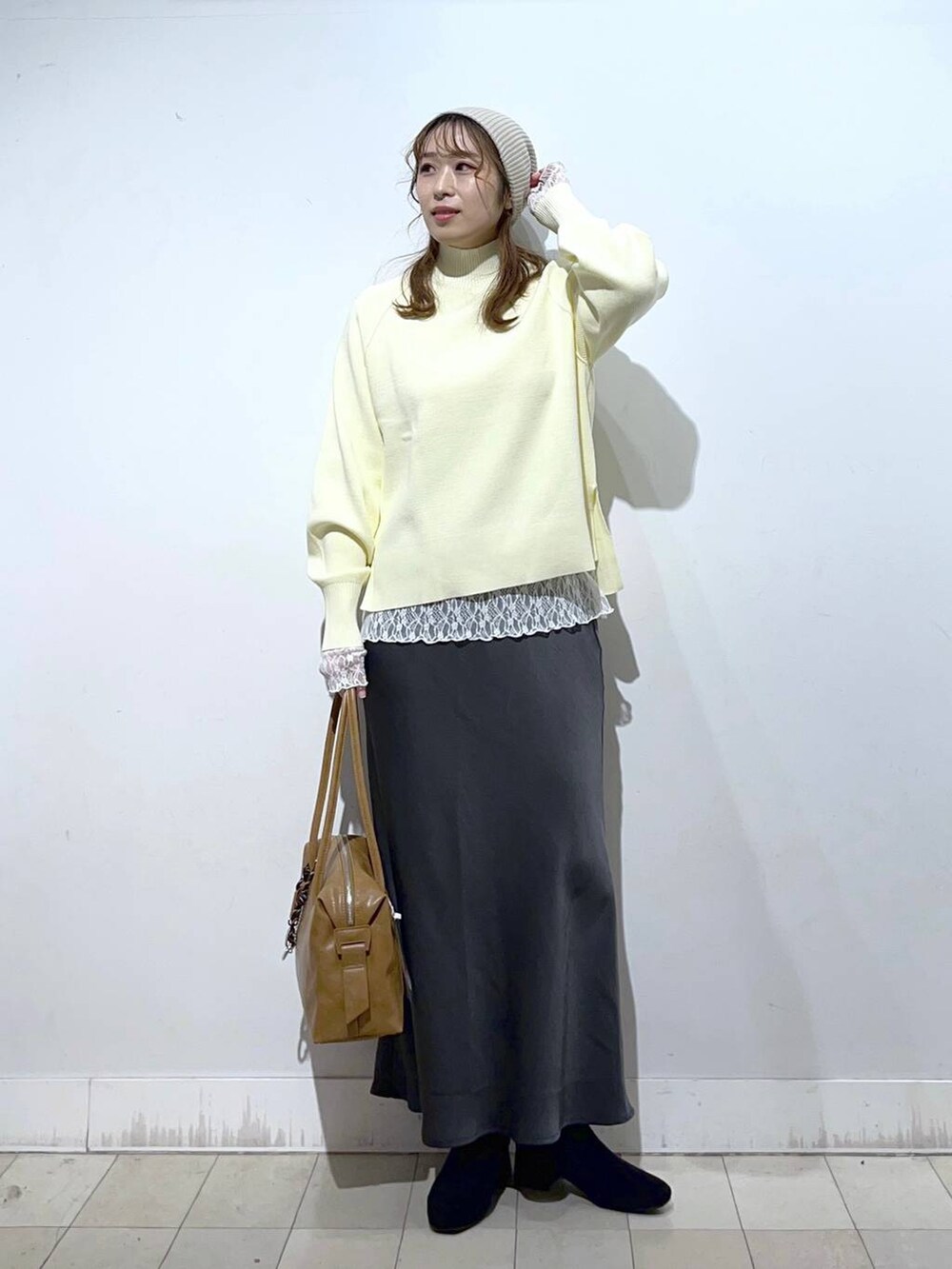 ブラウン系のボストンバッグ、ベージュ系のダウンジャケット/コート、ホワイト系のTシャツ/カットソーを着用したレディースの冬コーディネートの5枚目の写真