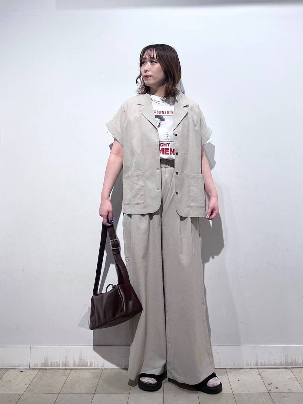 ブラウン系のショルダーバッグ、ベージュ系のその他パンツ、ホワイト系のTシャツ/カットソーを着用したレディースの夏コーディネートの5枚目の写真