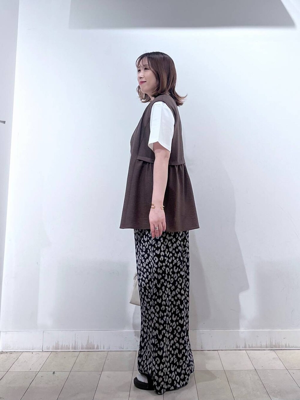 ベージュ系のショルダーバッグ、ブラウン系のベスト、その他のその他パンツを着用したレディースの夏コーディネートの2枚目の写真